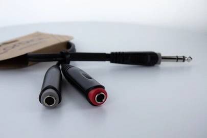Kabel audio z wtyczką 6,3 mm oraz dwoma gniazdami 6,3 mm, jeden z czerwonym, drugi z szarym złączem, na białym tle.