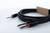Czarny kabel audio z dwoma wtyczkami jack 6,3 mm, jedną z czerwonym pierścieniem, drugą z czarnym pierścieniem, na białym tle.