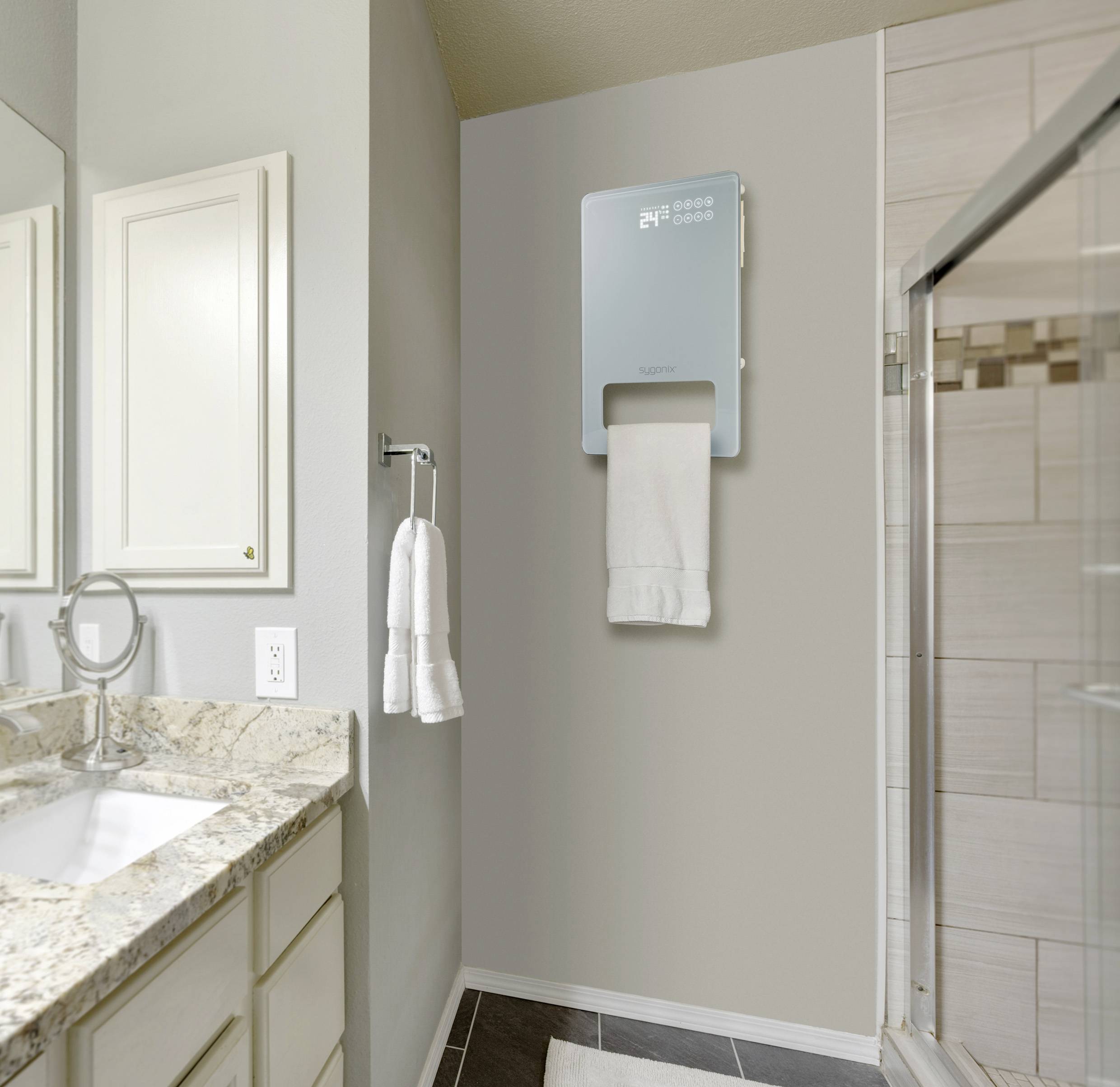 Łazienka z umywalką, lustrem i ręcznikami. Na ścianie wisi elektryczny suszacz do ręczników, na którym zawieszony jest jeden ręcznik.