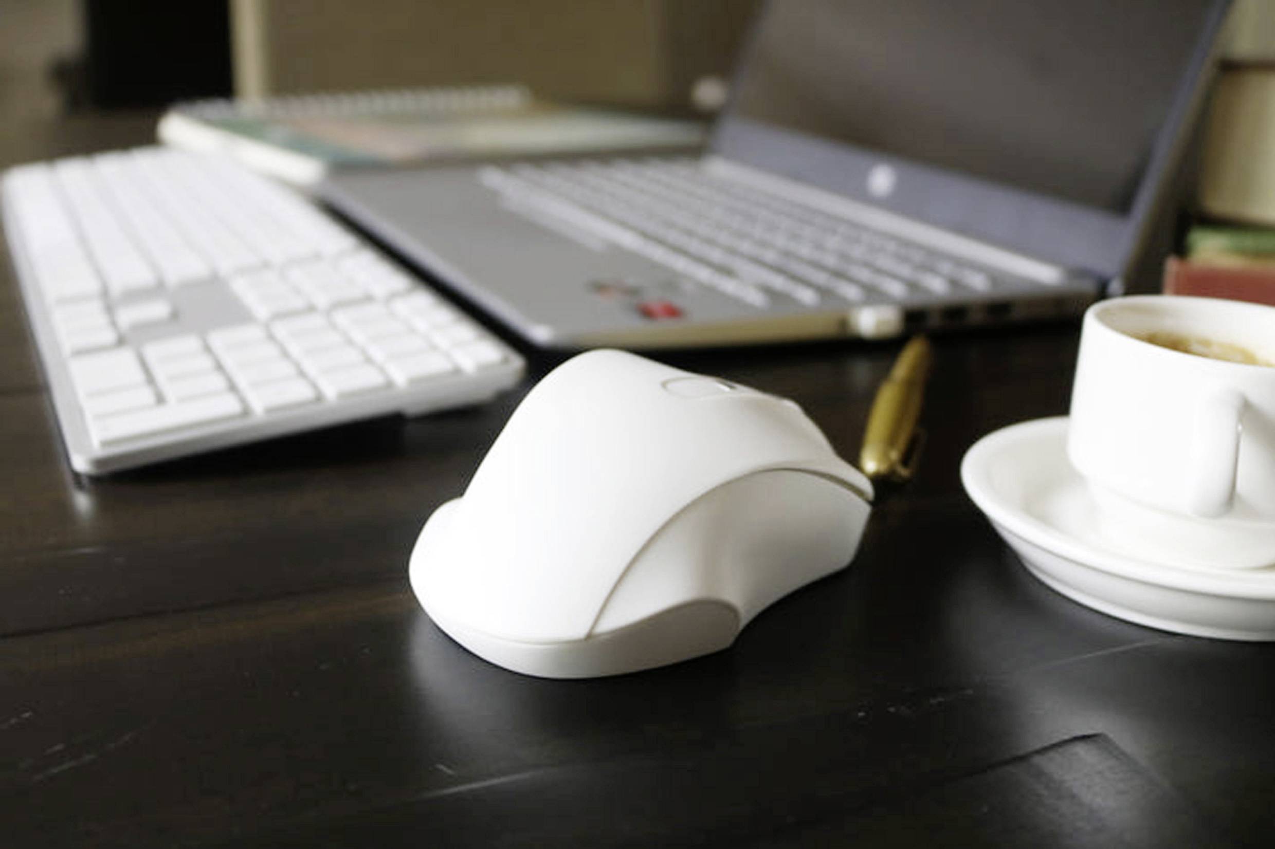 Laptop na drewnianym stole z myszą komputerową, klawiaturą i filiżanką kawy. Wyposażenie biura sprzyjające produktywnej pracy.