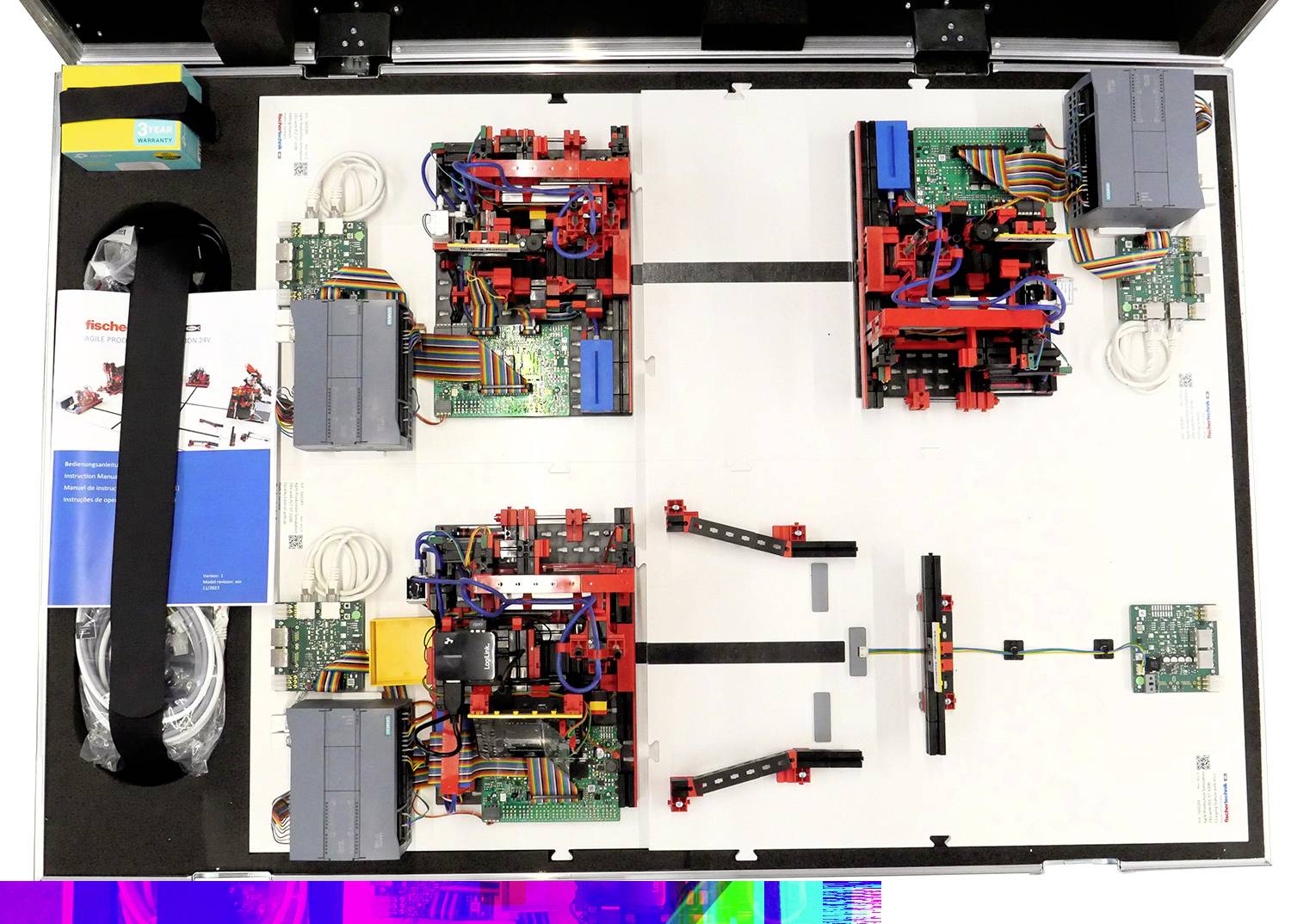 Elektroniczny zestaw eksperymentalny w otwartej walizce z różnymi modułami, przewodami i podręcznikiem po lewej stronie.