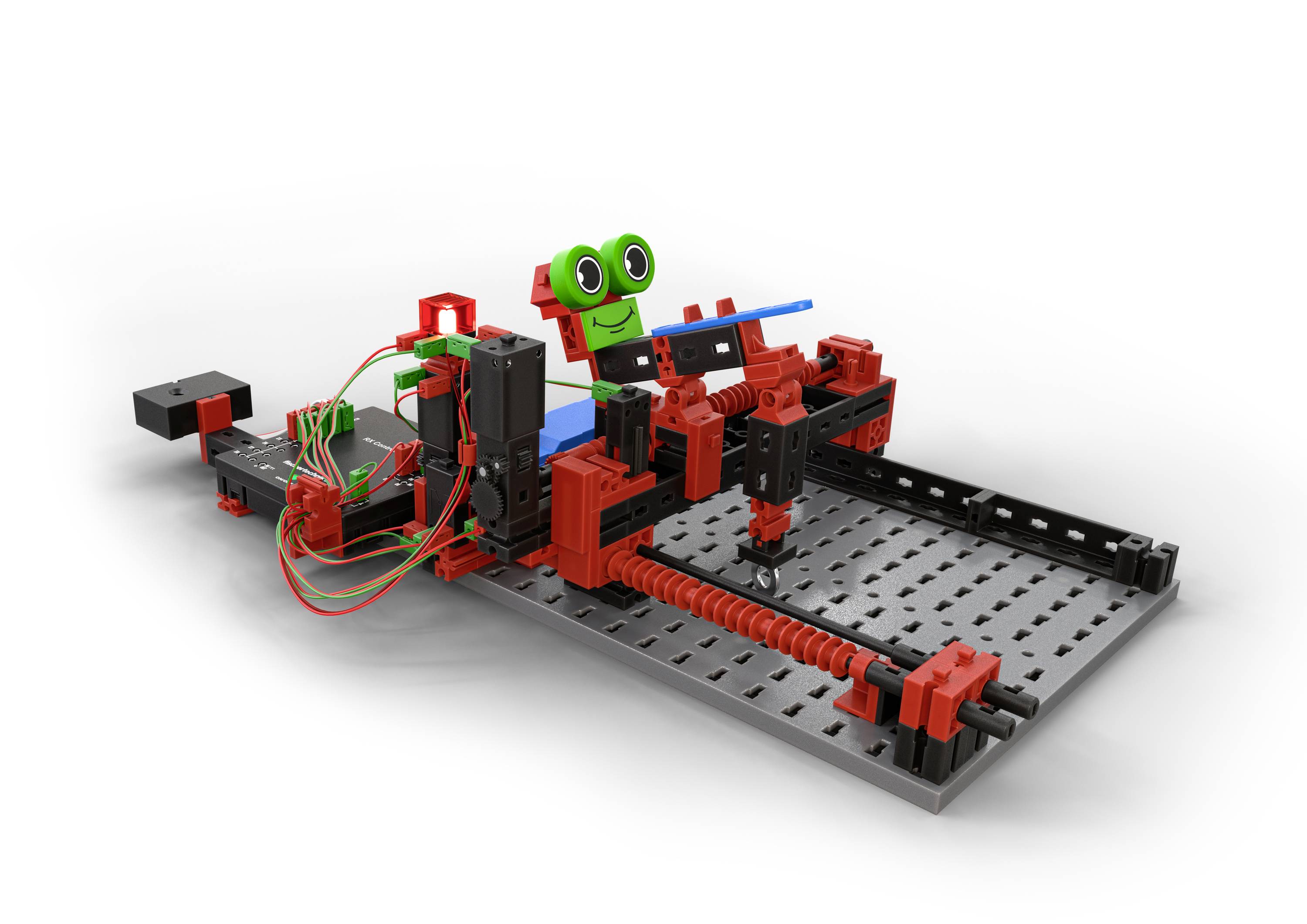 Robot z czerwonych i czarnych elementów siedzi na szarej platformie. Ma zielone oczy i jest podłączony kablami.