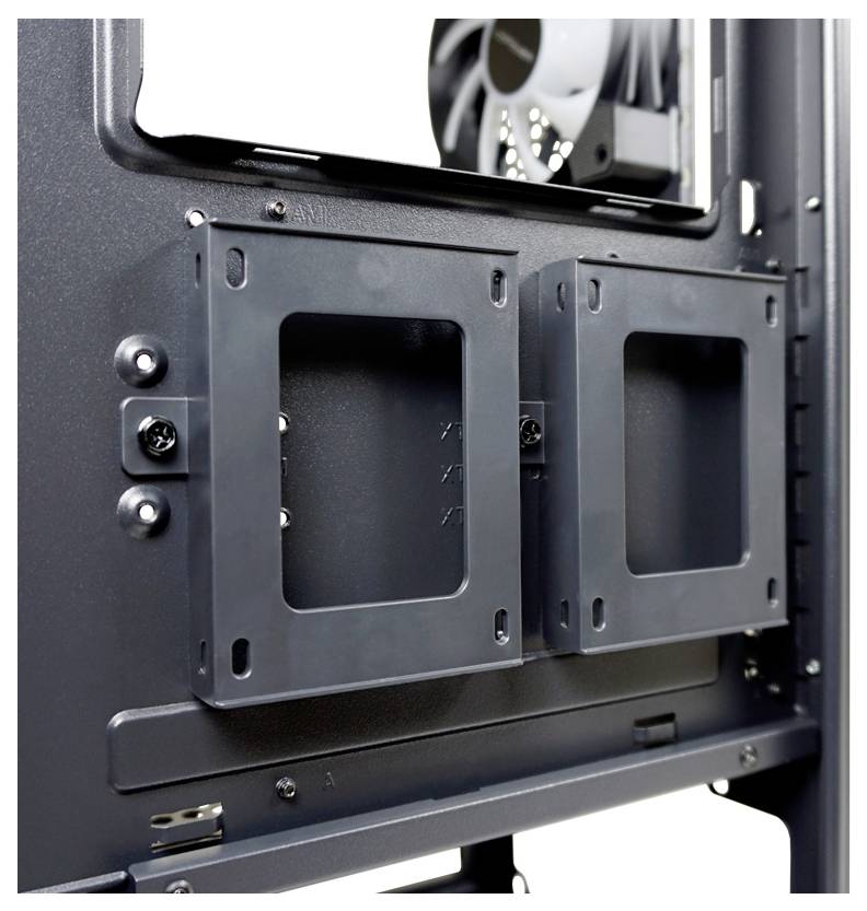 Wnętrze obudowy komputera z dwoma pustymi mocowaniami na dyski twarde lub SSD, z widocznymi wentylatorami w tle.