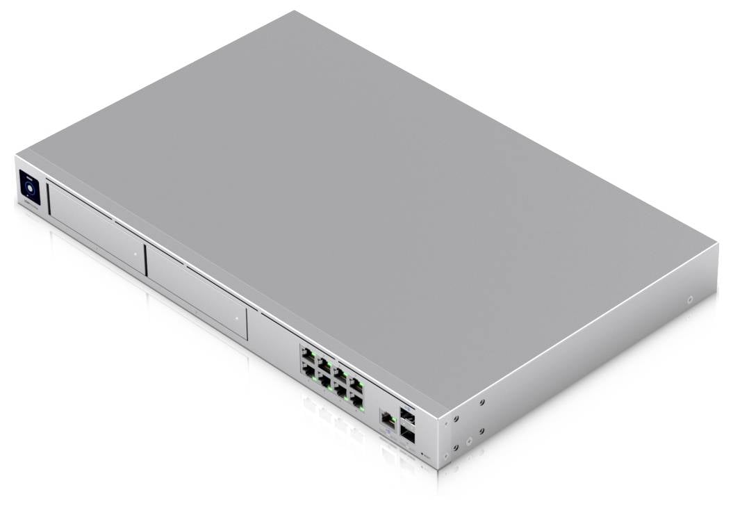 Srebrny przełącznik sieciowy z wieloma portami Ethernet i dwoma pustymi gniazdami z przodu, umieszczony na białej powierzchni.