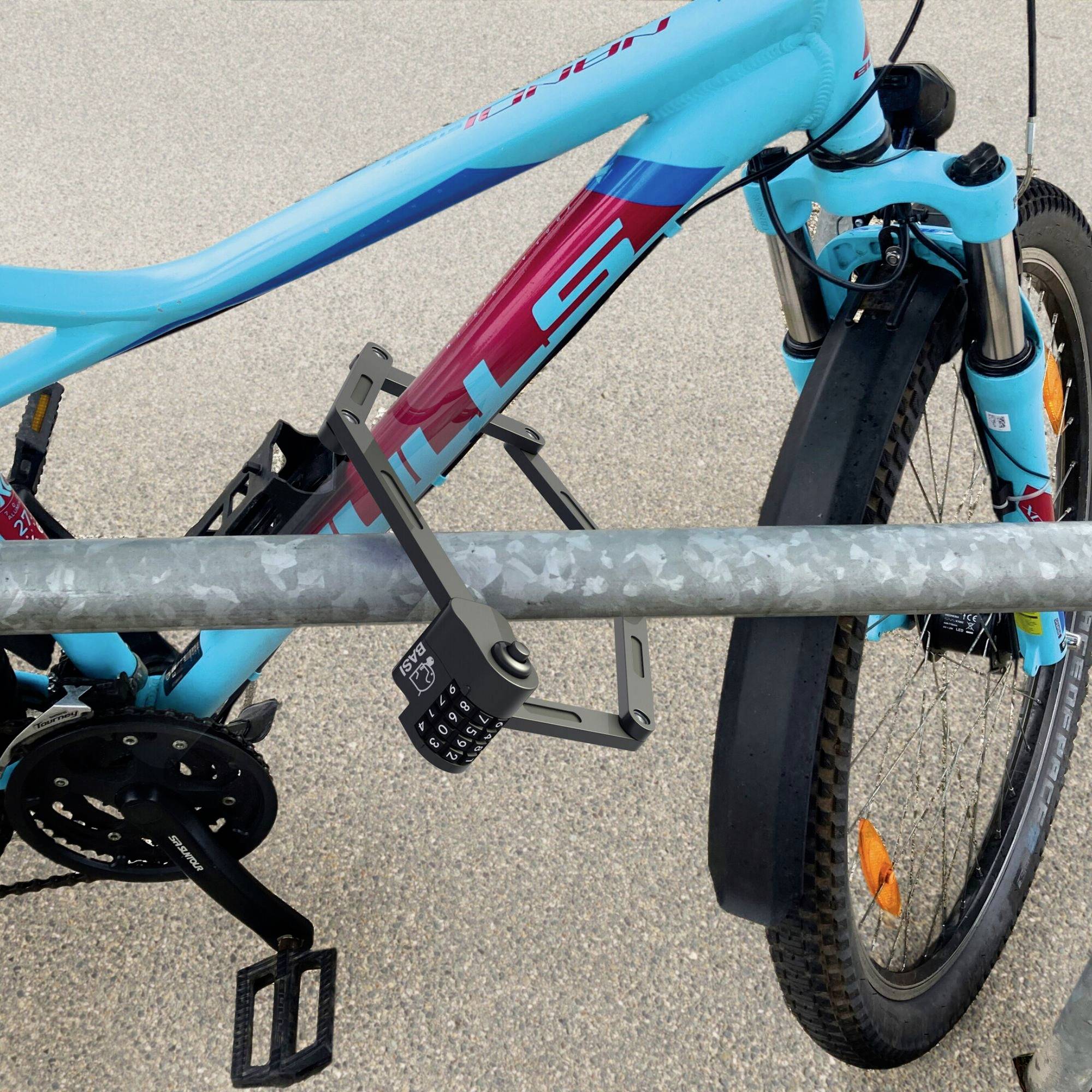 Niebieski rower jest zabezpieczony zamkiem szyfrowym przy metalowym stojaku. Przednie koło posiada pomarańczowe odblaski.