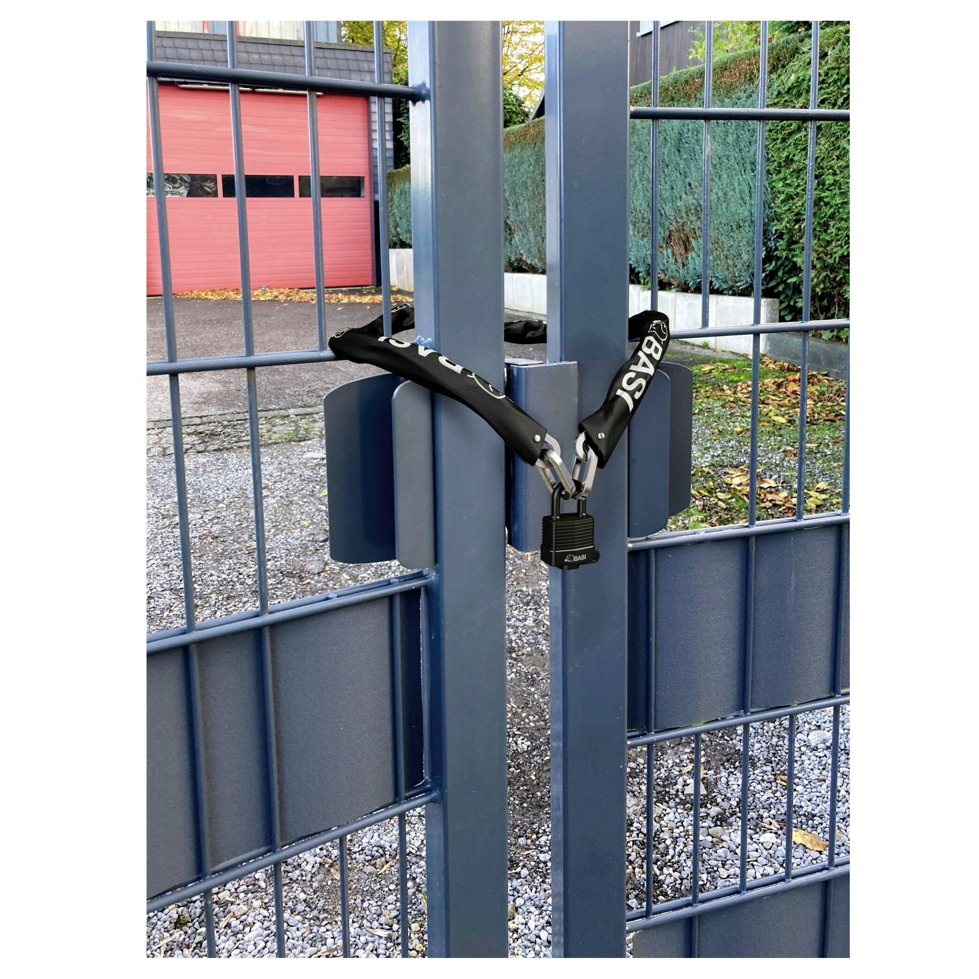 Niebieska metalowa brama jest zamknięta czarną kłódką zabezpieczoną łańcuchem. W tle widoczne są budynki.