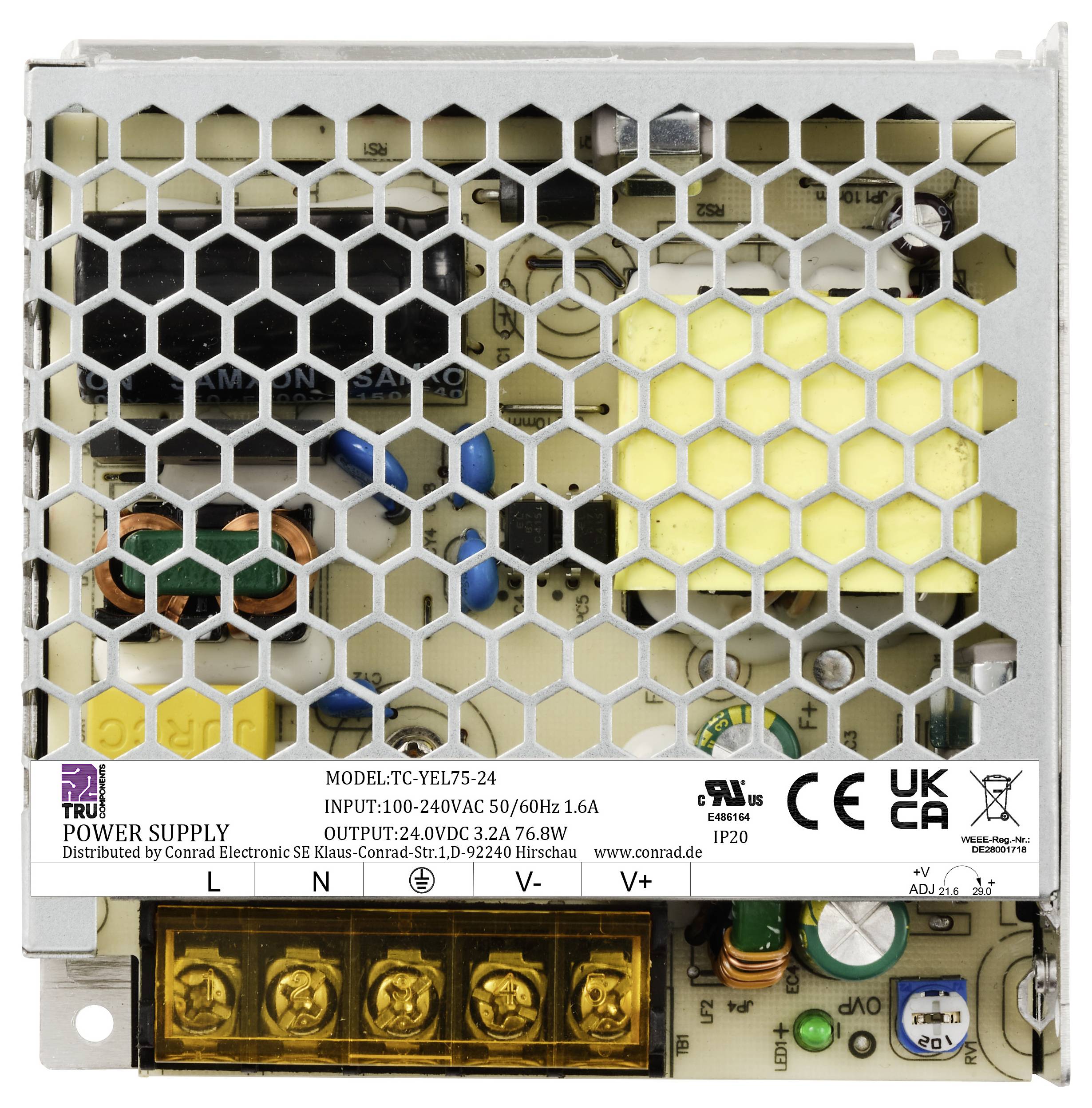 Obudowa zasilacza z kratką osłonową i elementami elektronicznymi w środku; widoczna etykieta ze specyfikacjami i symbolami ochronnymi.