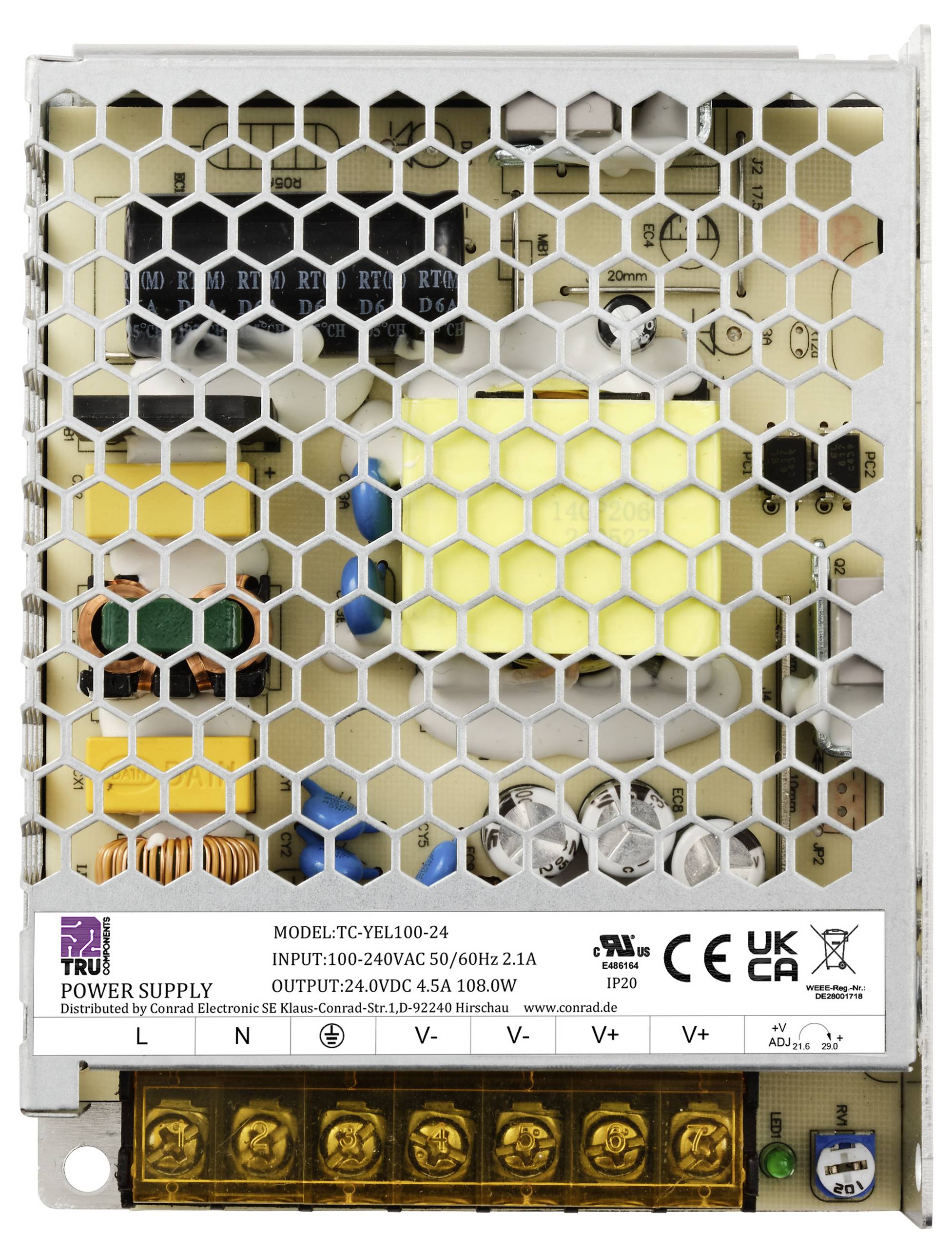 Jednostka zasilająca z osłoną w kształcie plastra miodu. Etykieta wskazuje model: TC-VEL100-24, napięcie wejściowe/wyjściowe oraz znaki bezpieczeństwa.