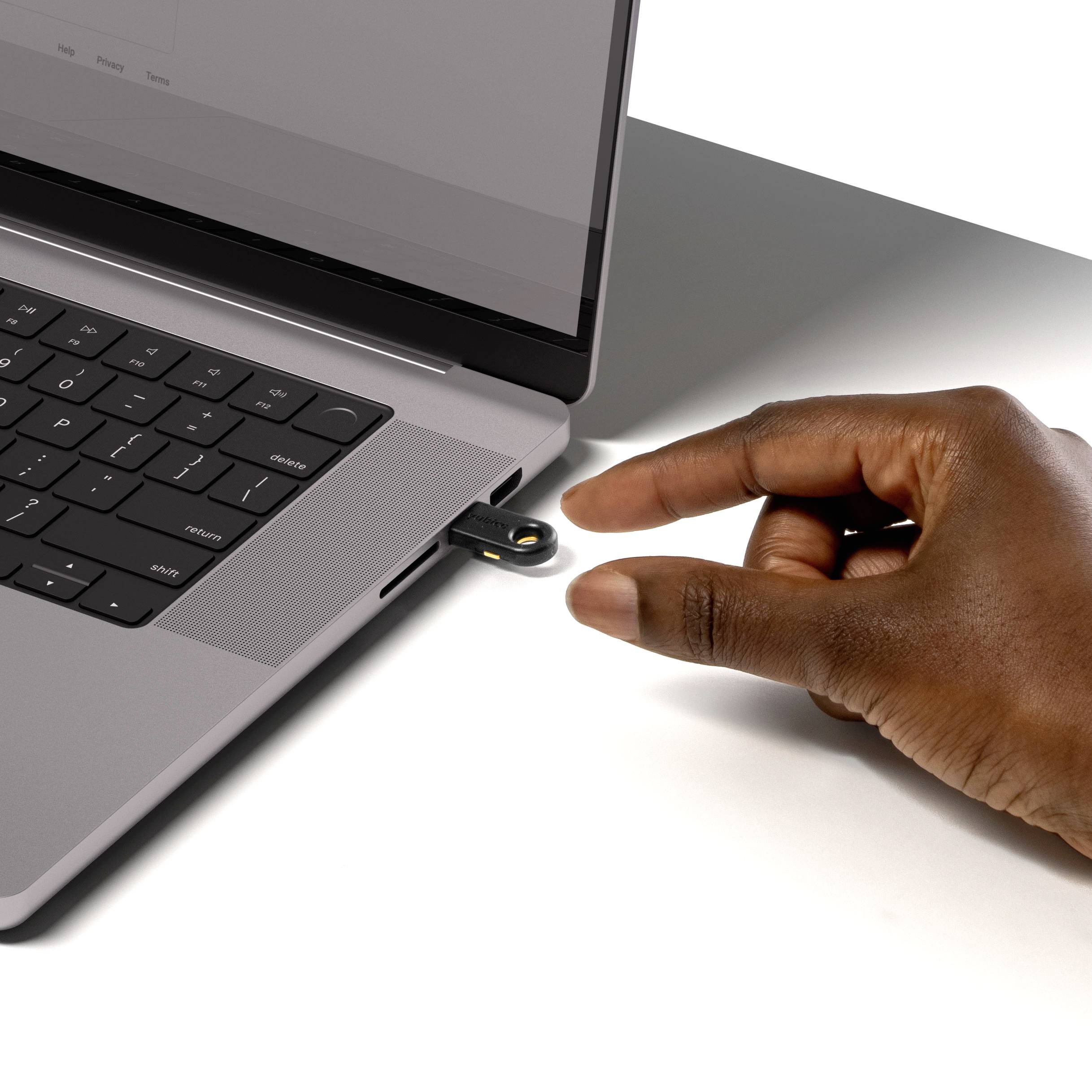 Dłoń wkłada pendrive do portu USB laptopa. Ekran laptopa nie jest wyraźnie widoczny, fokus skierowany jest na złącze USB.