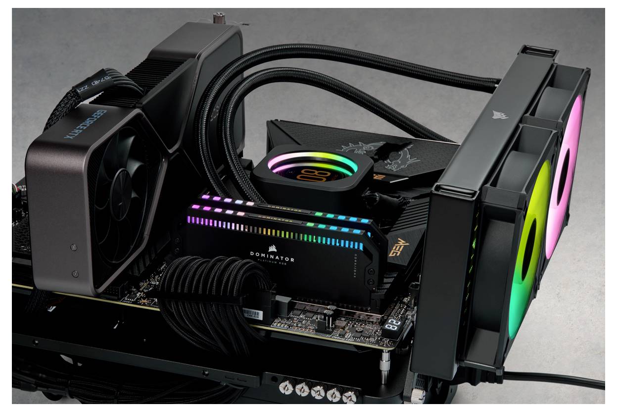 Komputer z otwartą obudową prezentuje chłodzenie wodne i kolorowe komponenty RGB. Kable są starannie ułożone.