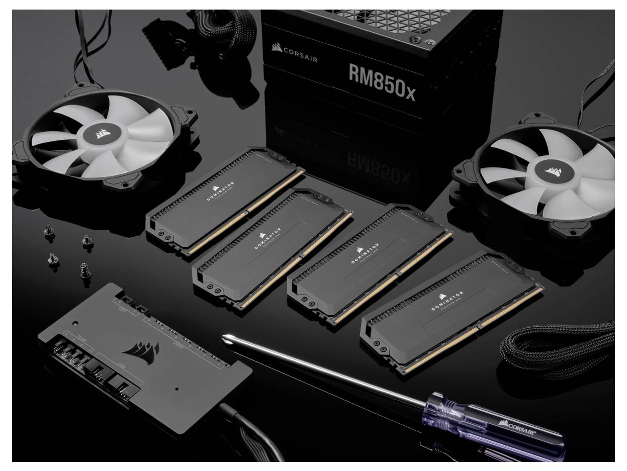 Komponenty komputerowe, w tym wentylatory chłodzące, moduły RAM, zasilacz oraz śrubokręt na czarnym tle.