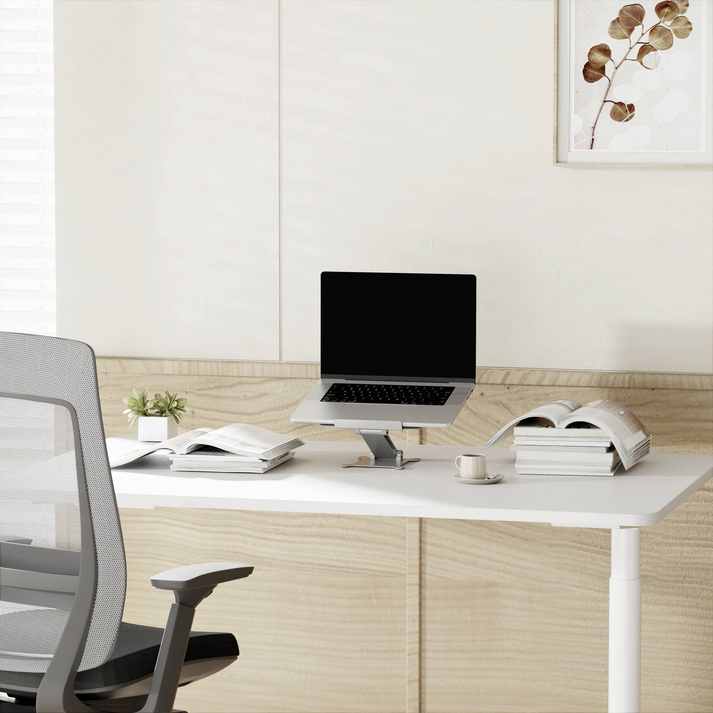 Jasne biuro z białym biurkiem, na którym leży laptop, otwarty książka i filiżanka. W tle wisi obraz.