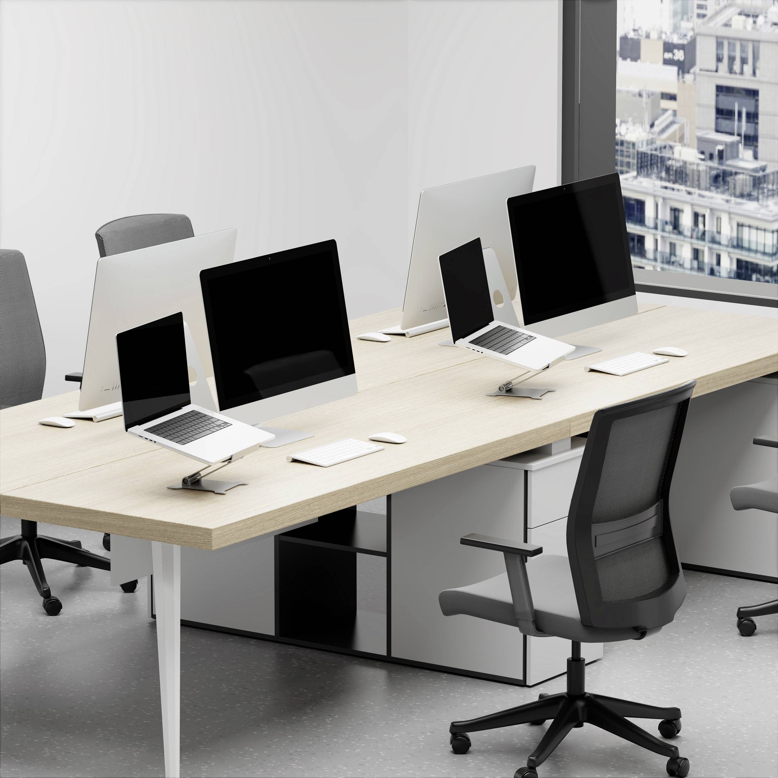Nowoczesna przestrzeń biurowa z trzema stanowiskami pracy, każde wyposażone w czarne monitory i laptopy. Duże okna ukazują widok na miasto w tle.