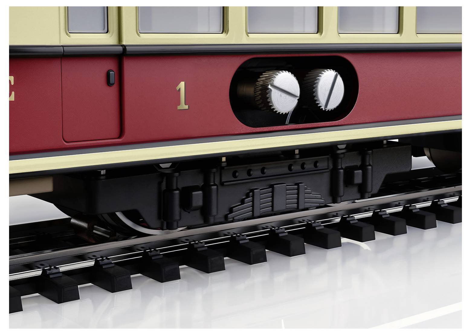 Zbliżenie czerwonego pociągu z kołami zębatymi po bokach, osadzonymi na szynach. Ujęcie przedstawia historyczny detal wagonu.