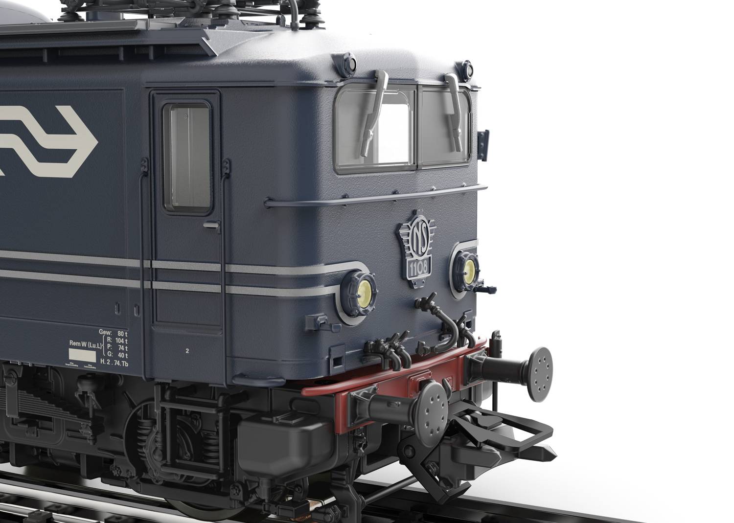 Zbliżenie ciemnej lokomotywy modelowej na torach, z wyrazistymi reflektorami i szczegółowymi metalowymi strukturami.