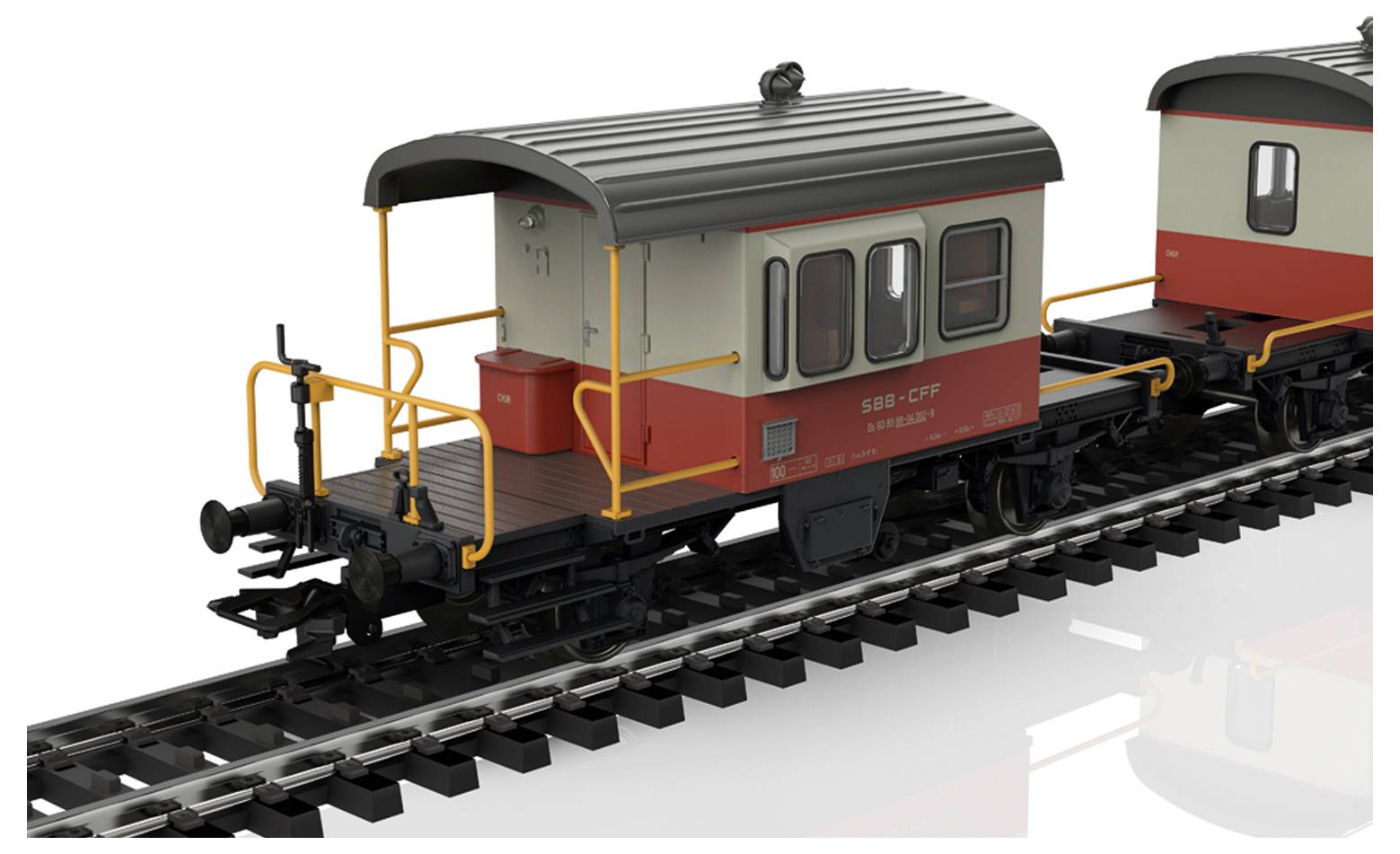 Stary wagon towarowy w kolorze czerwono-beżowym z czarnym dachem, stojący na torach. Widoczne są żółte barierki bezpieczeństwa.