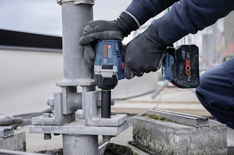 Osoba używa elektrycznego wkrętarko-wiertarki do zamocowania metalowych elementów konstrukcji.