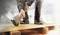 Osoba używa łomu, aby podnieść deski. Sceneria wskazuje na plac budowy. Osoba nosi odzież ochronną.