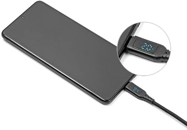 Smartfon podczas ładowania, ekran wyłączony. Powiększenie ukazuje cyfrowy wyświetlacz na kablu ładującym z informacją '30%'.