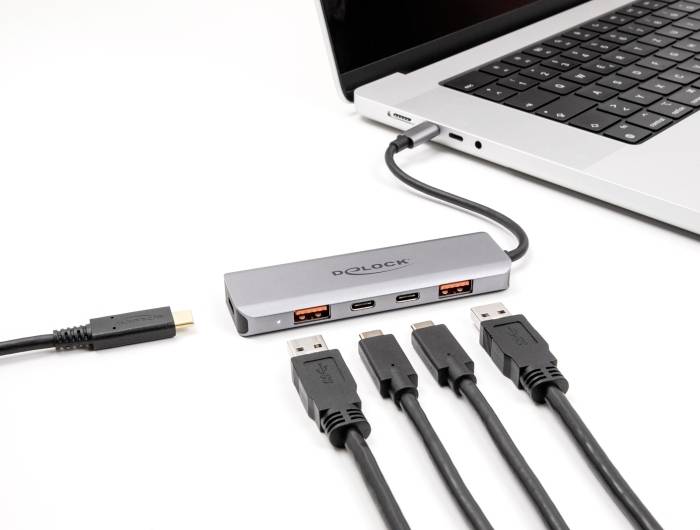 Laptop jest podłączony do concentratora USB-C, który oferuje wiele portów USB i kabli, aby rozszerzyć możliwości połączeniowe.