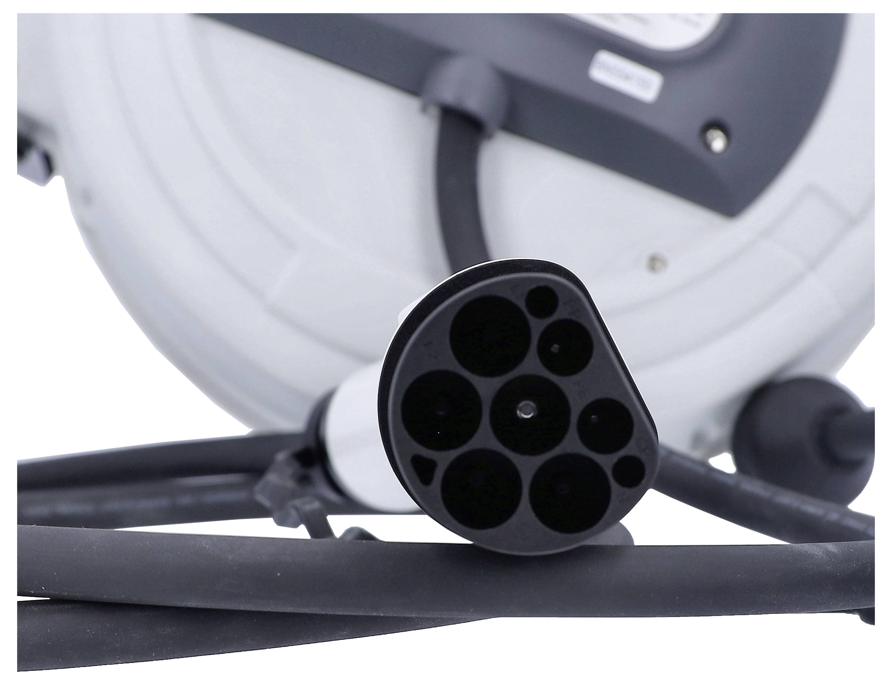 Zbliżenie wtyczki elektrycznej i długiego czarnego kabla na tle stacji ładującej.