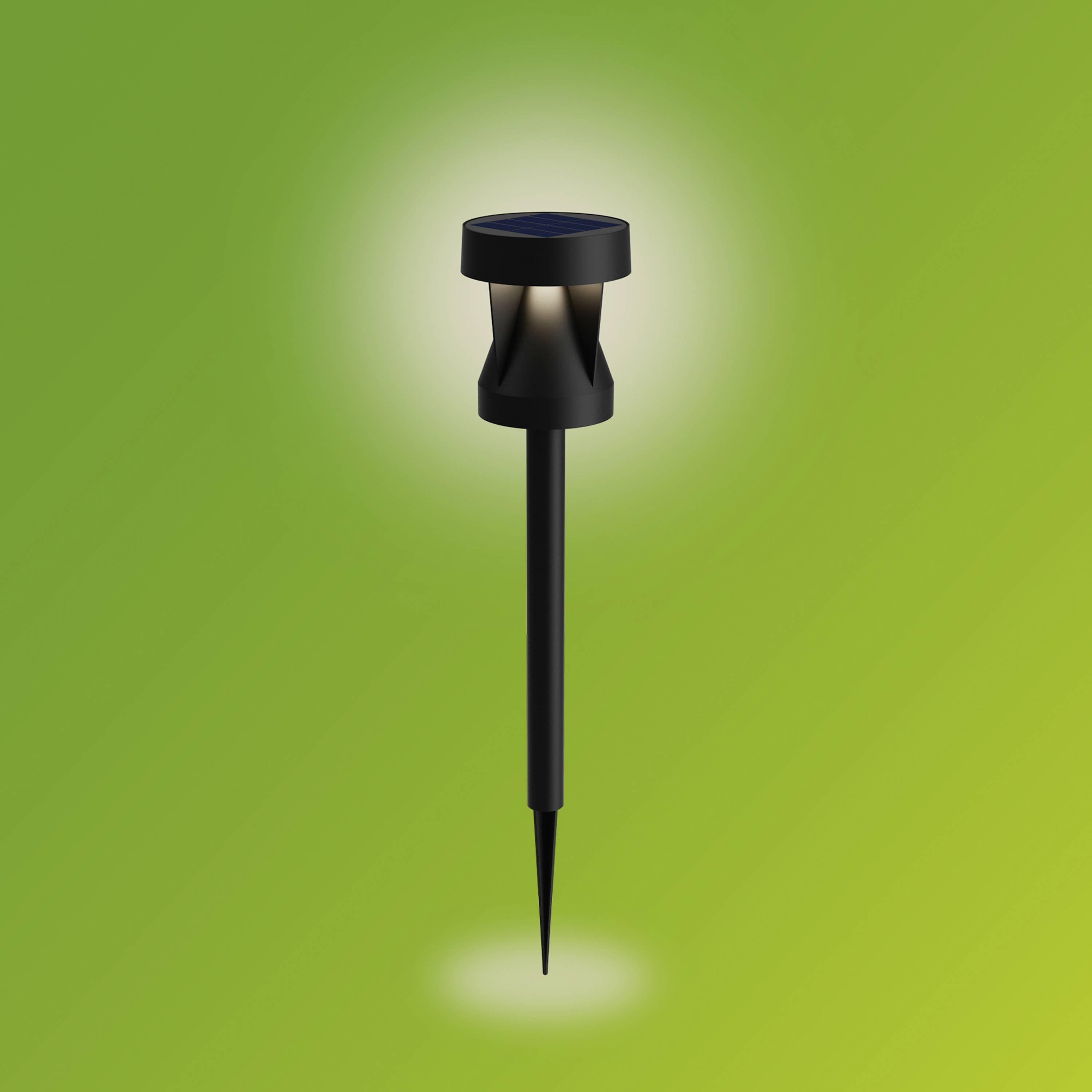 Solarna lampa ogrodowa świecąca jasno na zielonym tle. Idealna do oświetlenia przestrzeni zewnętrznych.