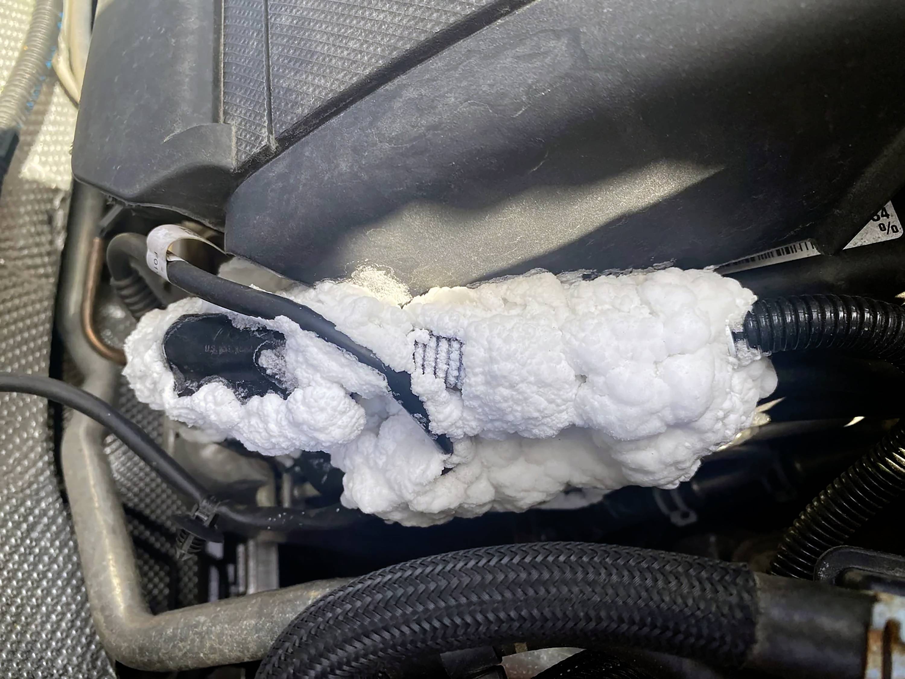 Izolacja z pianki wokół wiązki przewodów w komorze silnika; zapewnia ochronę i izolację termiczną; nasłonecznienie widoczne.