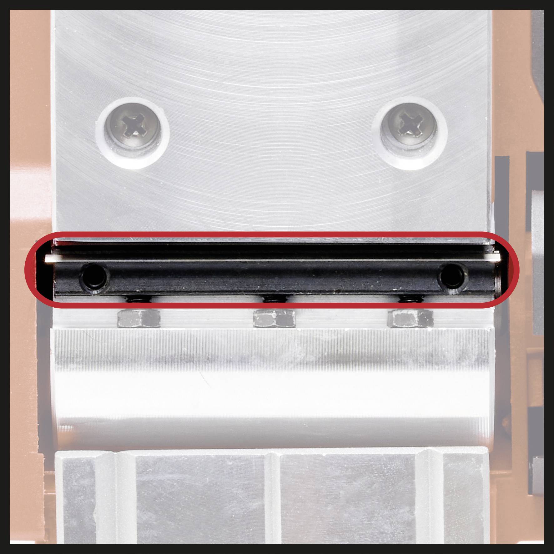 Zdjęcie mikroskopowe metalowej płyty z dwiema śrubami, obramowane czerwoną linią. Fokus spoczywa na czarnym pasku w centrum.