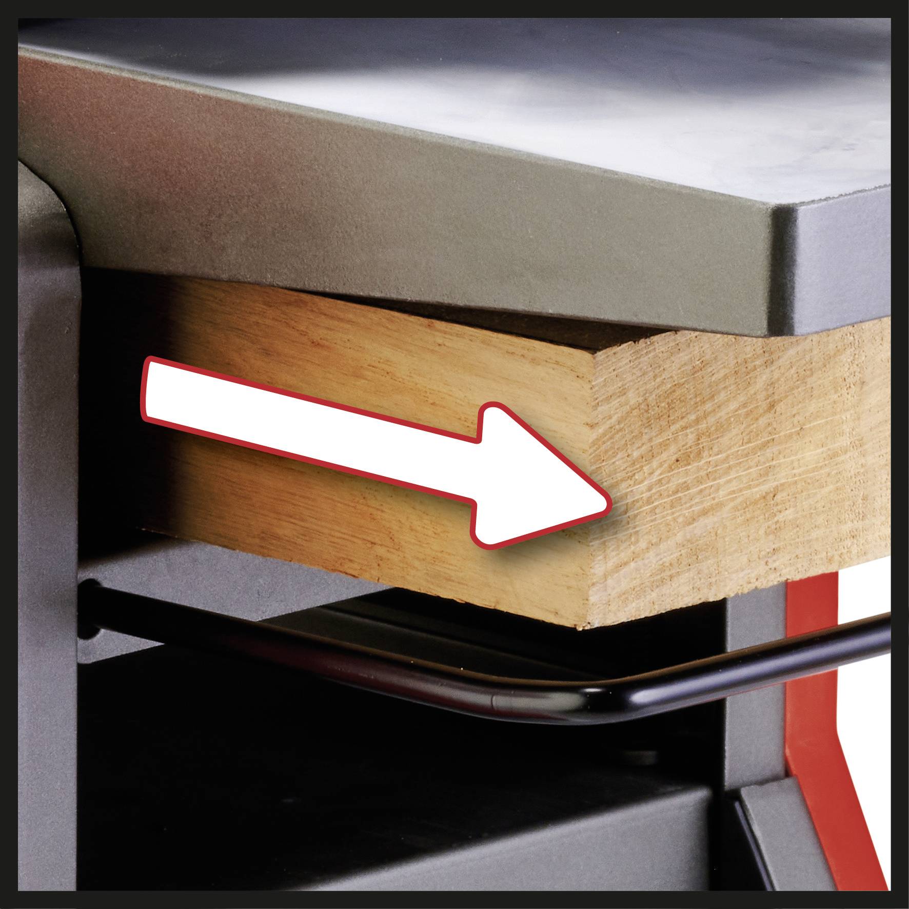 Drewniany blok oznaczony czerwoną strzałką. Strzałka wskazuje na krawędź bloku, prawdopodobnie w celu podkreślenia.