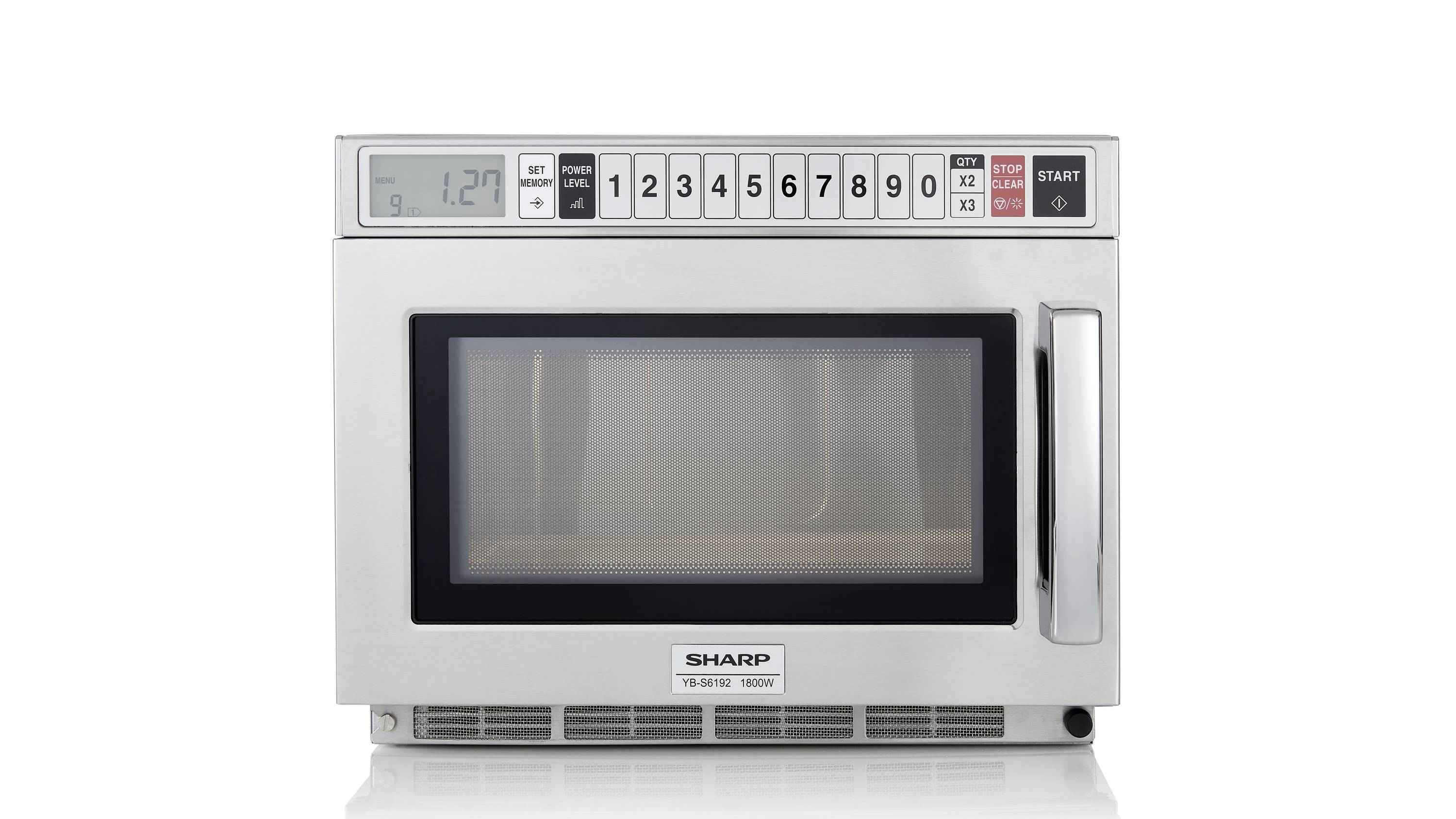 Mikrofalówka z cyfrowym wyświetlaczem czasu w lewym górnym rogu i numerowanymi przyciskami powyżej. Marka 'Sharp' widoczna jest na dole.