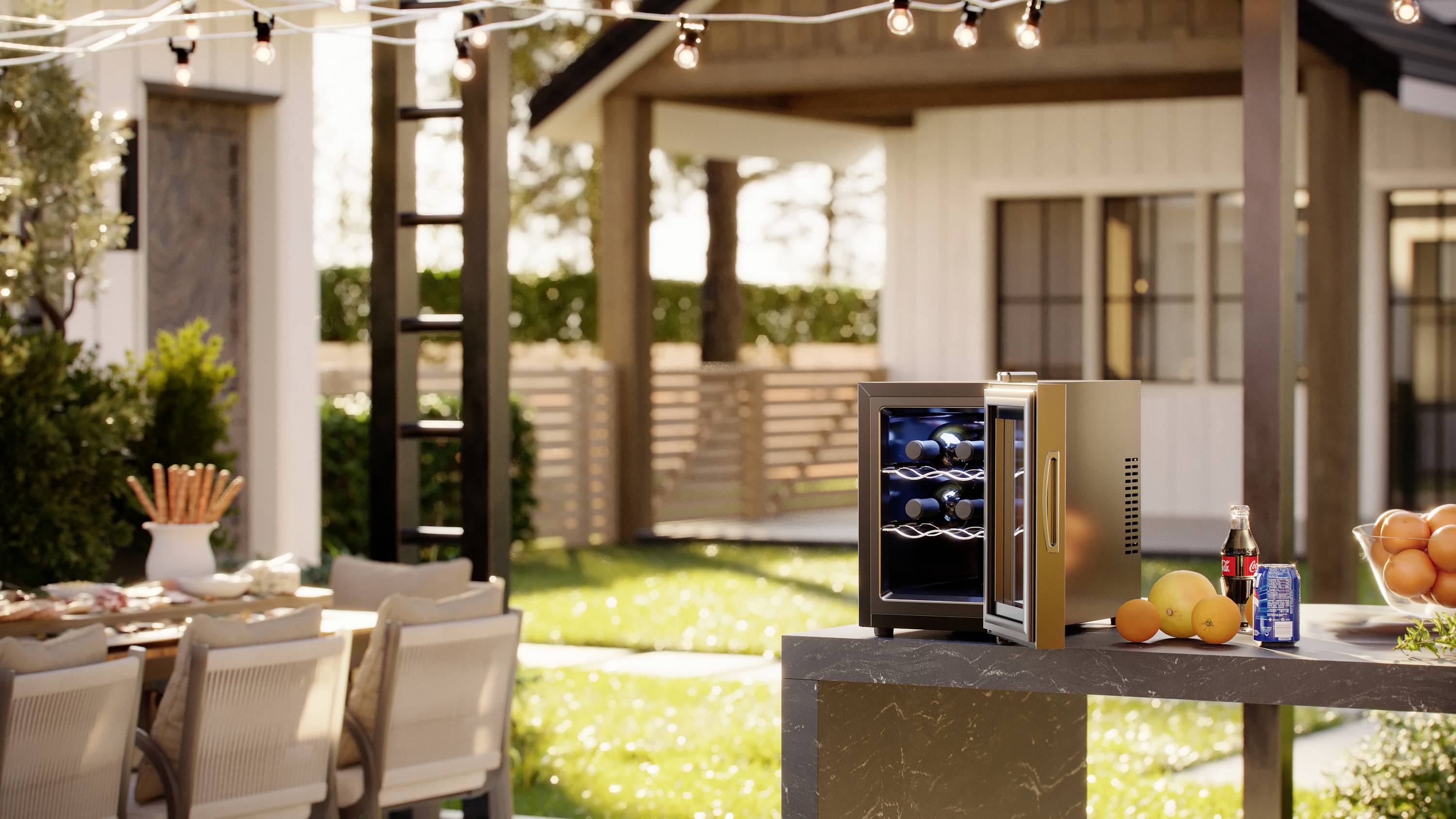 Nowoczesny ogród z nakrytym stołem. Na pierwszym planie mały lodówka z butelkami, otoczona owocami.