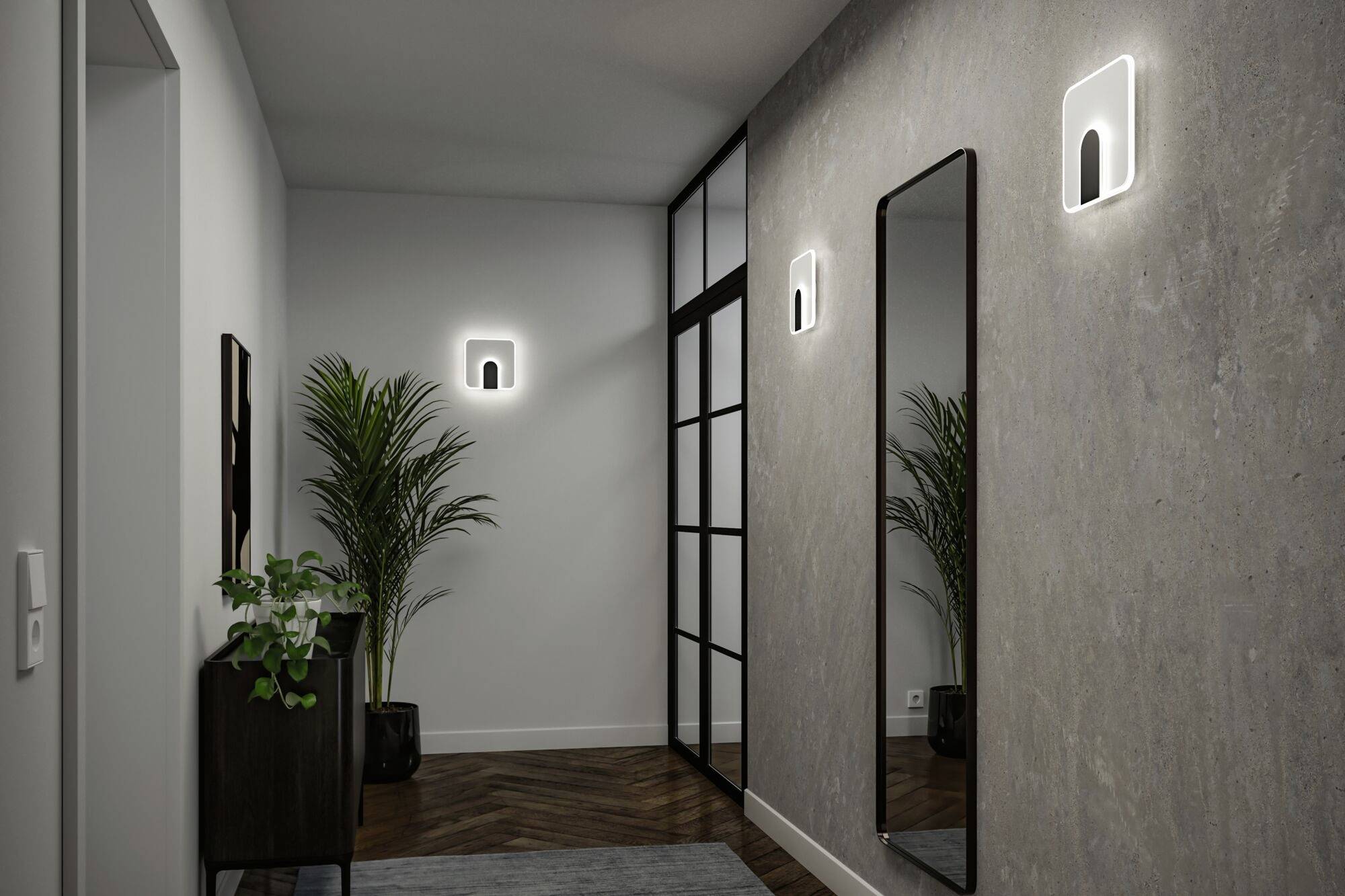 Nowoczesny korytarz z dwoma kinkietami, dużym lustrem i roślinami na drewnianej podłodze. Szklana ściana dzieli przestrzeń.