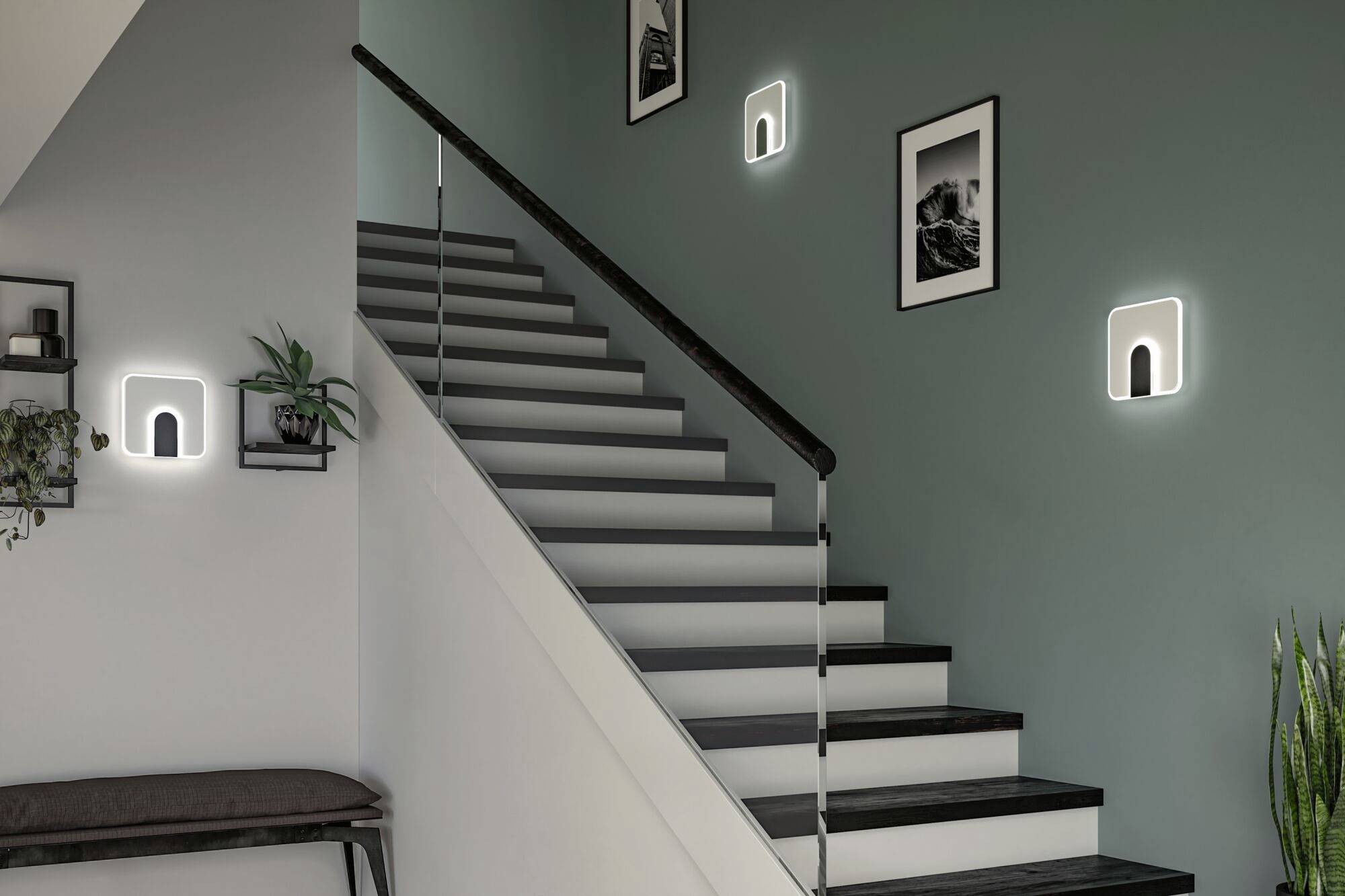 Schody z nowoczesnym oświetleniem ściennym, roślinami i ramkami na zdjęcia na zielonej ścianie.