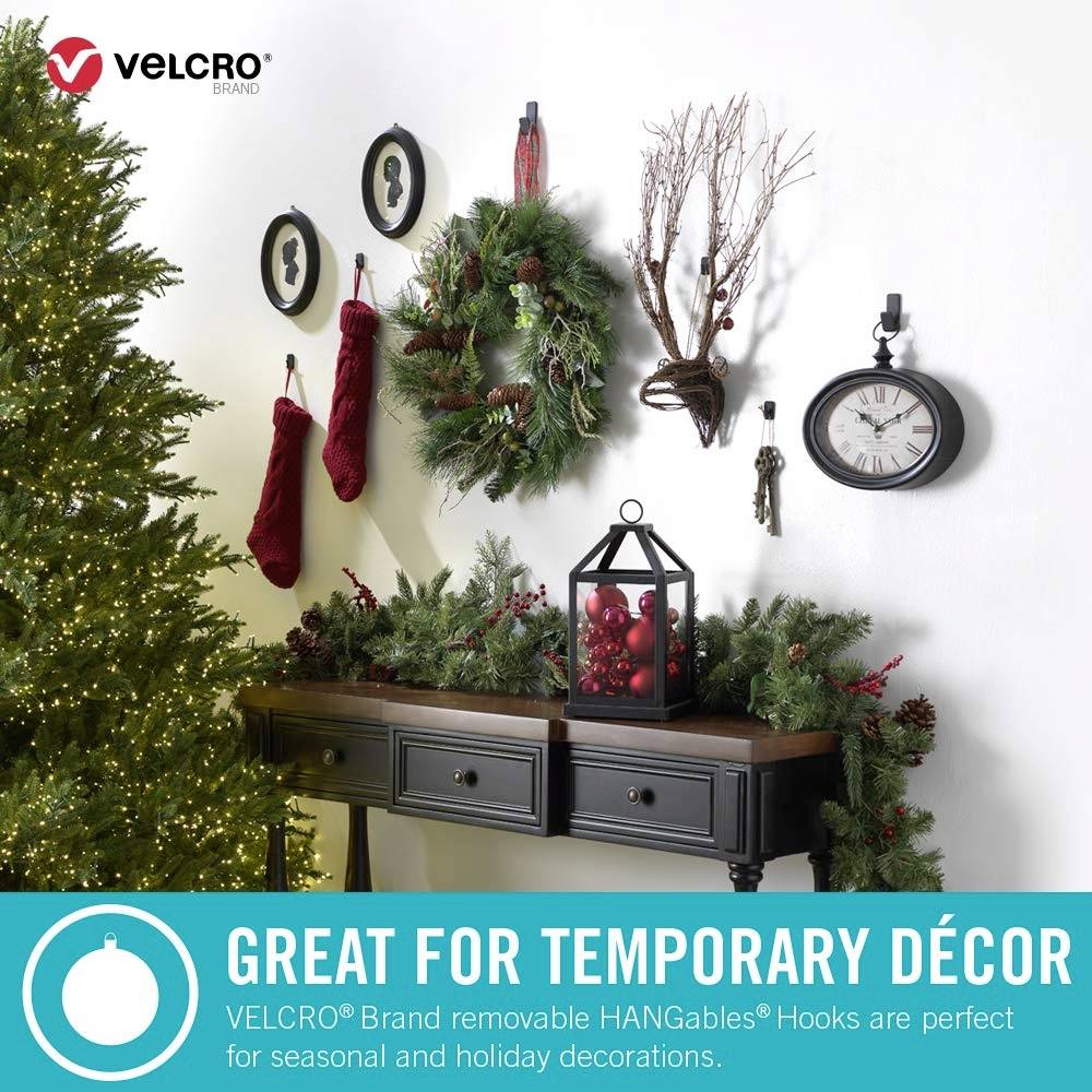 Salon świątecznie udekorowany choinką, girlandami świetlnymi, wieńcem, skarpetami i wieszakiem na ubrania. Na ścianie widnieje napis 'VELCRO'.