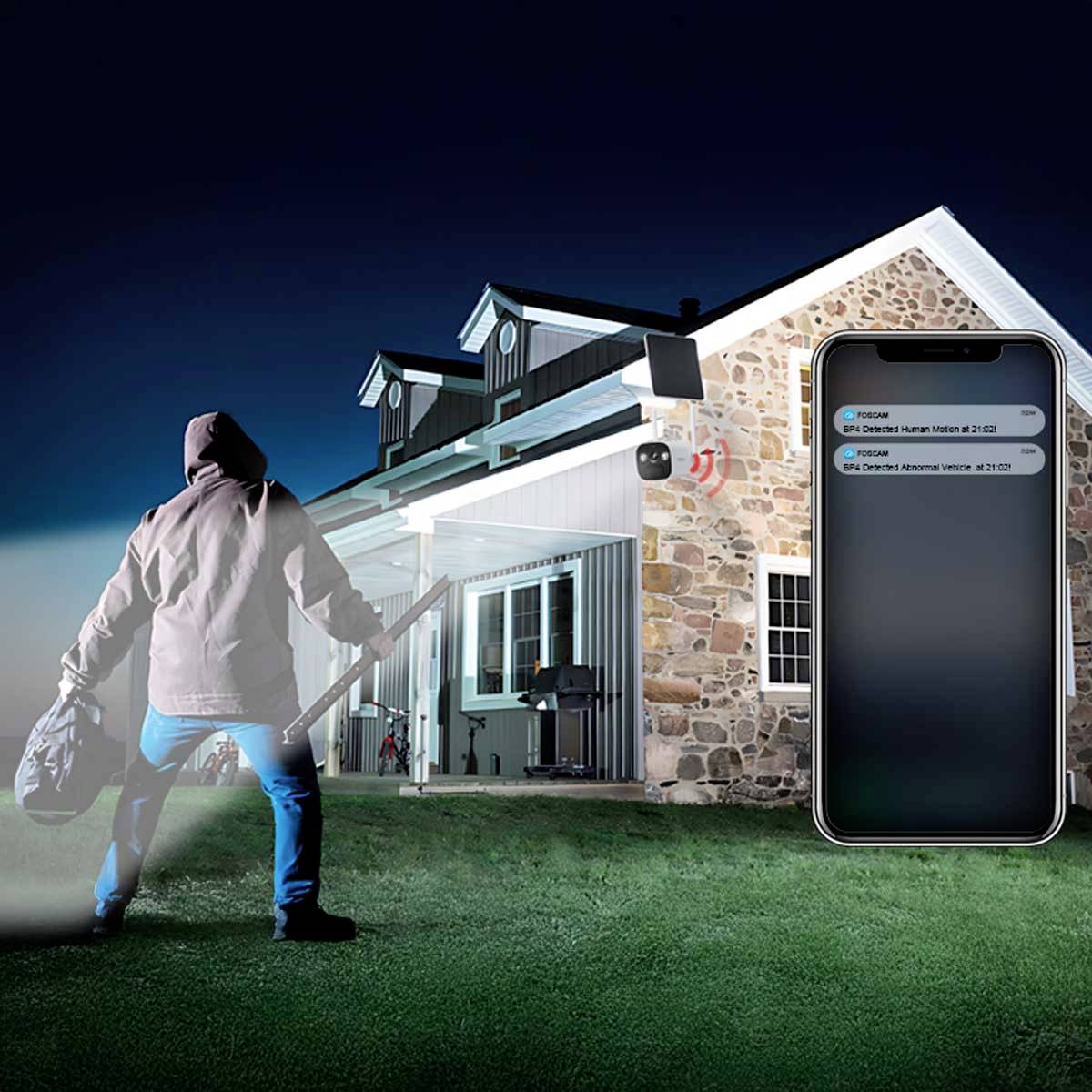 Włamywacz w kapturze zbliża się do domu. Powiadomienie na telefonie wyświetla 'Wykryto ruch', co wskazuje na aktywny system alarmowy.