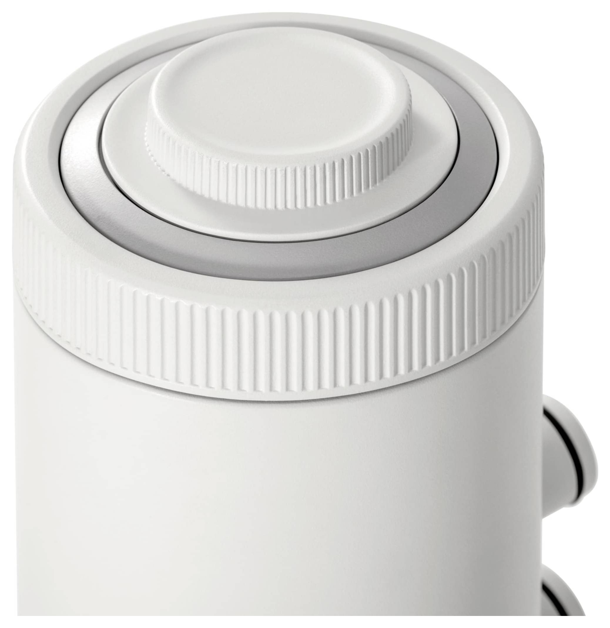 Biały pokrętło na cylindrycznym urządzeniu, prawdopodobnie mikrofonie lub podobnym sprzęcie audio, sfotografowany z góry.