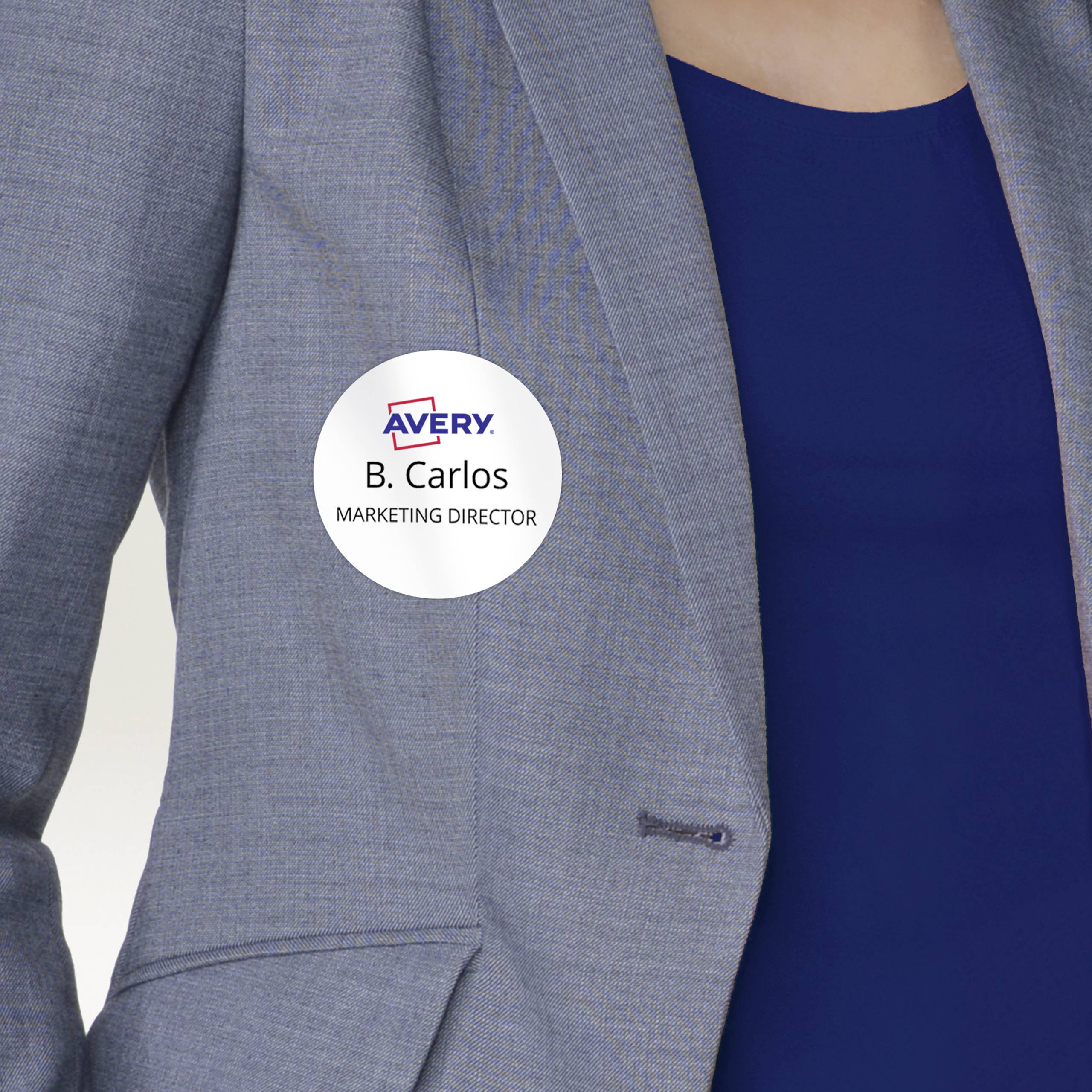 Osoba nosi identyfikator z napisem 'B. Carlos, Dyrektor ds. Marketingu' na szarym żakiecie na niebieskiej koszuli.