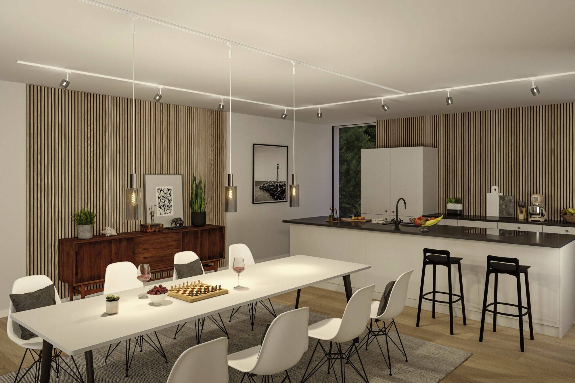 Nowoczesna jadalnia z długim białym stołem, otoczonym białymi krzesłami. W tle kuchnia z wyspą i hokerami. Subtelne oświetlenie.