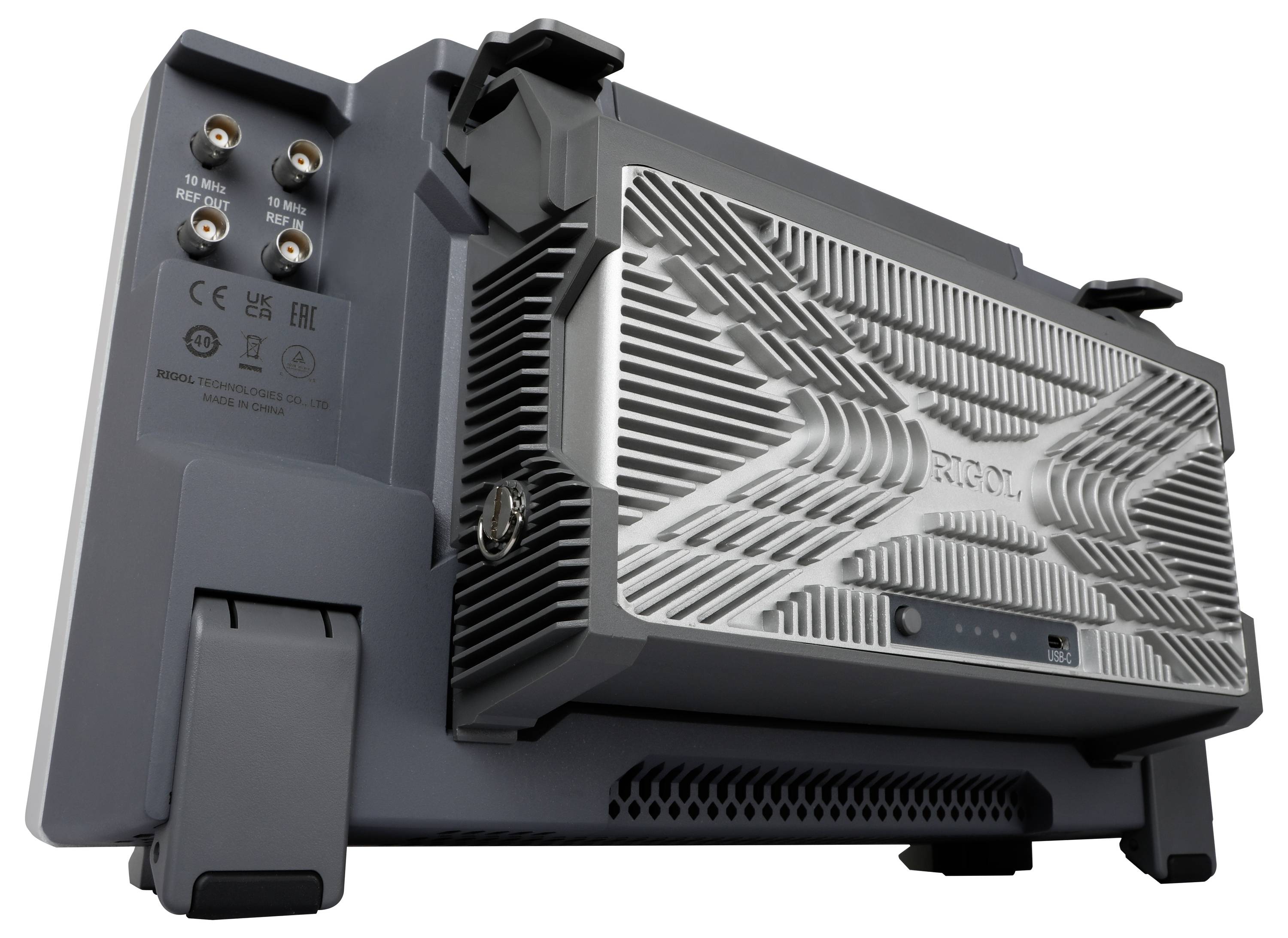 Szare urządzenie techniczne z wieloma portami i charakterystyczną, metalową kratką wentylacyjną z boku.