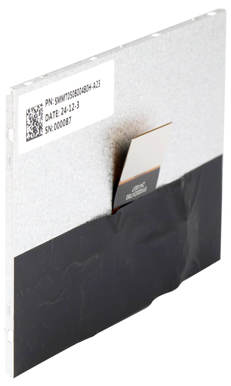 Srebrny element elektroniczny z czarną taśmą na spodzie. Etykieta zawiera numer modelu, datę oraz numer seryjny.