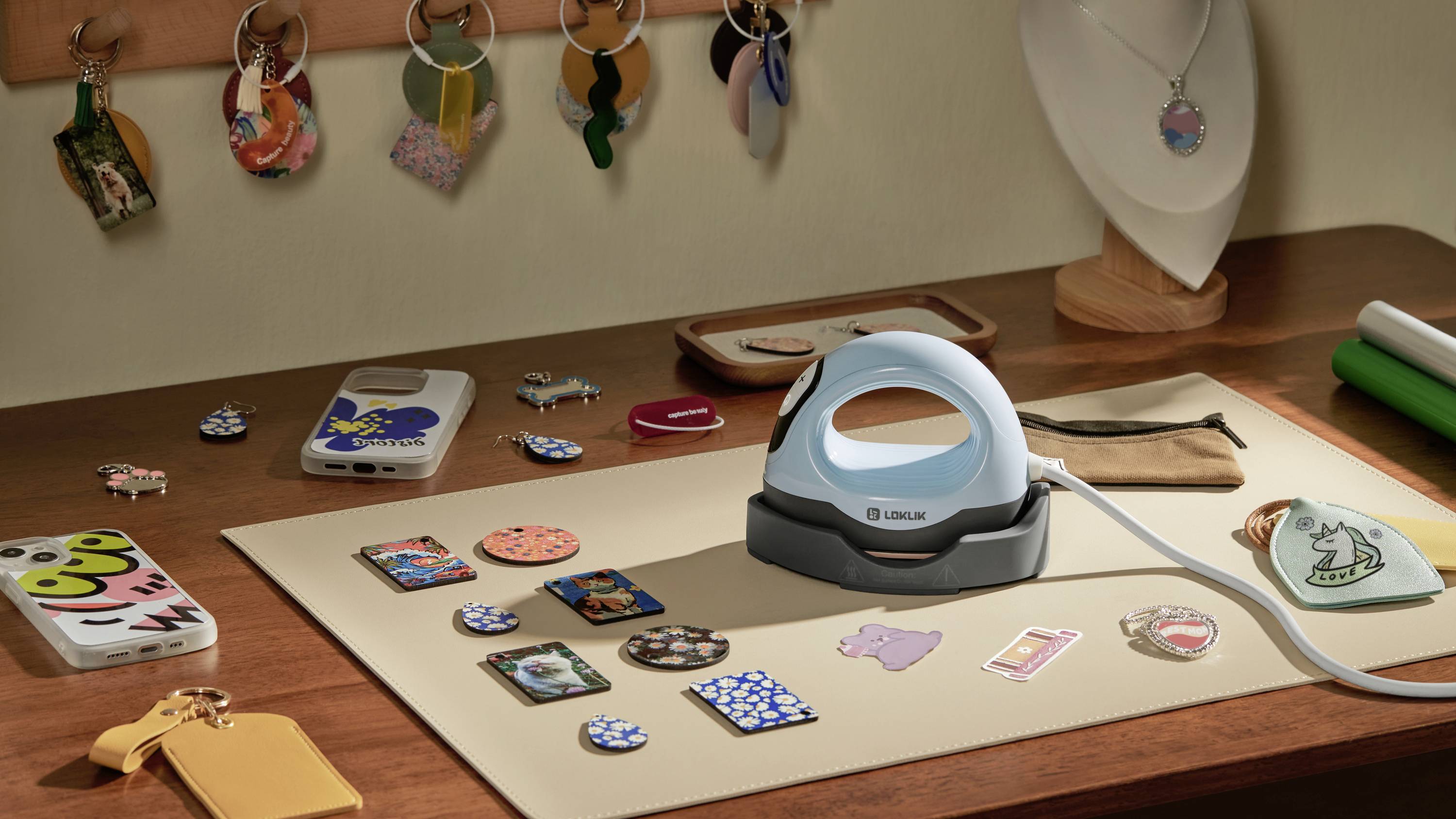 Stolik z małym żelazkiem, otoczony breloczkami, naklejkami i akcesoriami do telefonu. Drewniany stojak przechowuje biżuterię.