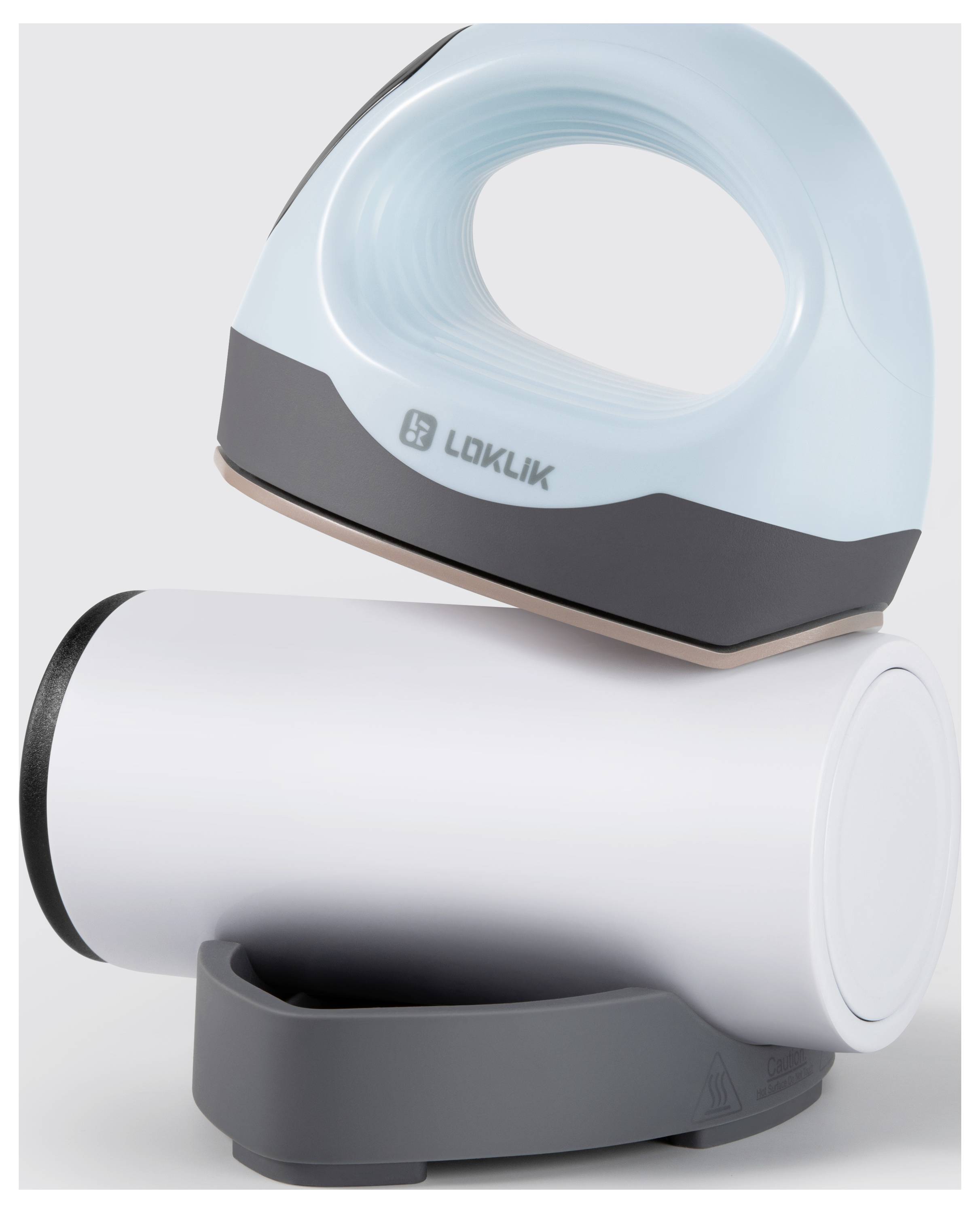 Kompaktowe, nowoczesne żelazko z białym korpusem i jasnoniebieskim uchwytem leży bokiem na szarej podstawie.