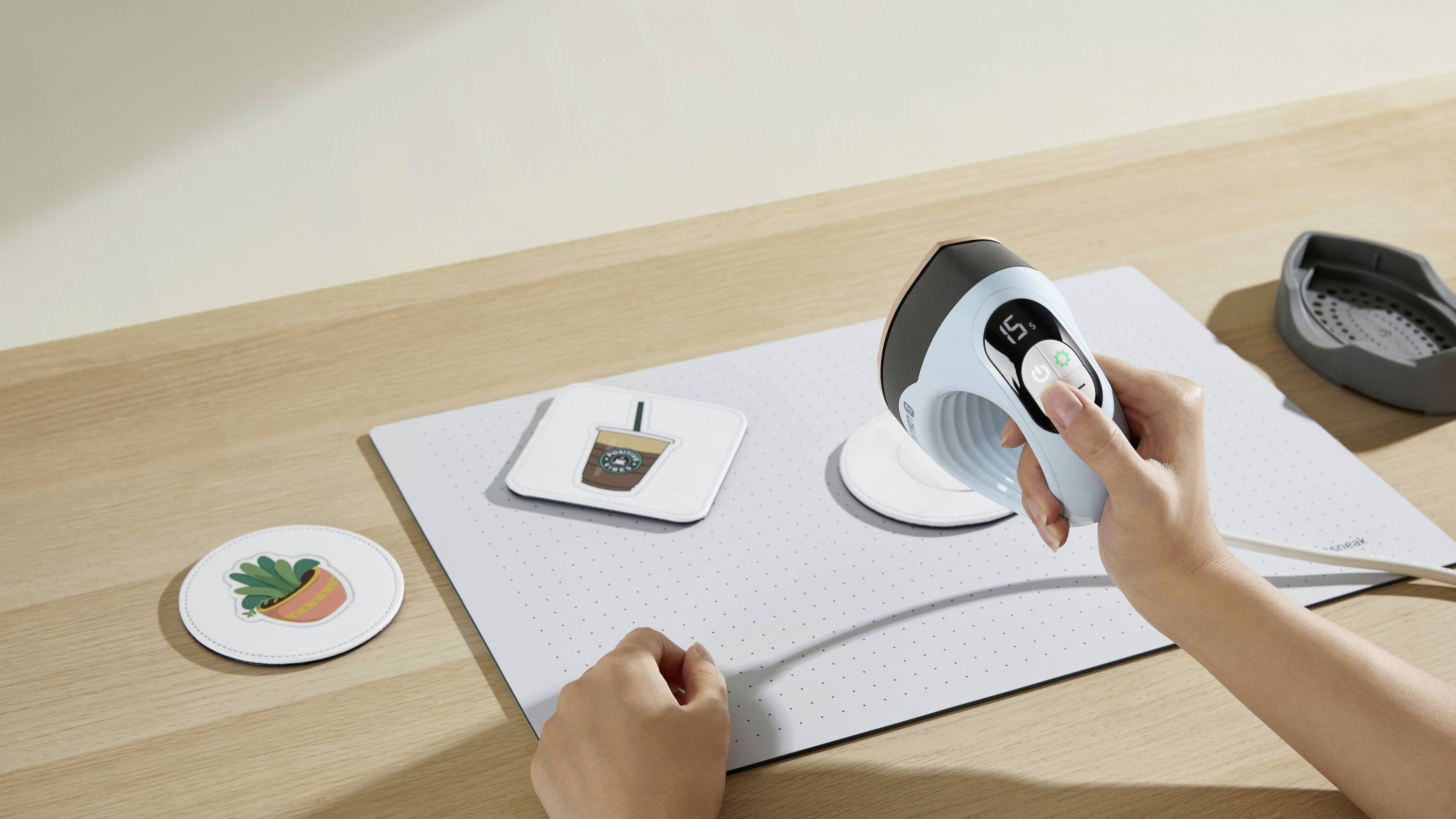 Osoba skanuje okrągłe etykiety z ilustracjami napoju i rośliny na płaskiej, jasnej powierzchni.