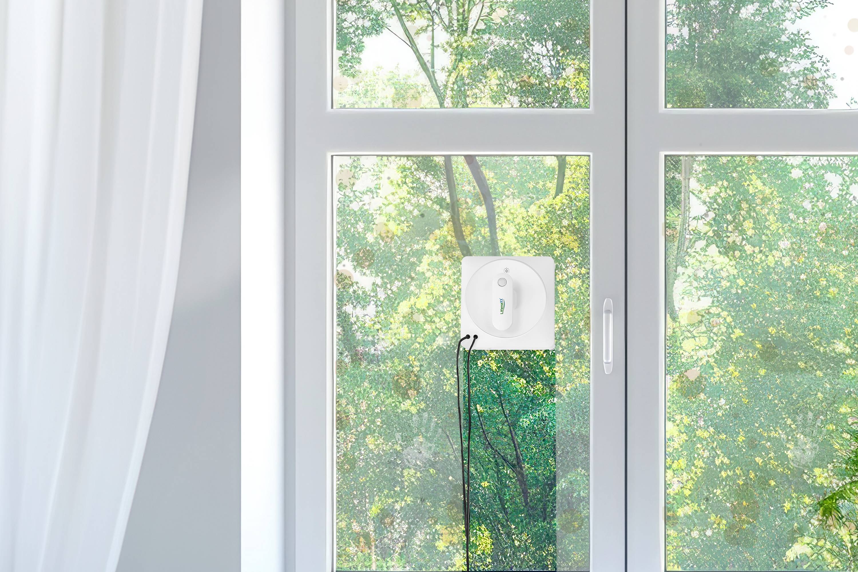 Automatyczny robot do czyszczenia okien jest zamocowany na dużej tafli szkła. Na zewnątrz widać drzewa i zieloną zieleń liści.