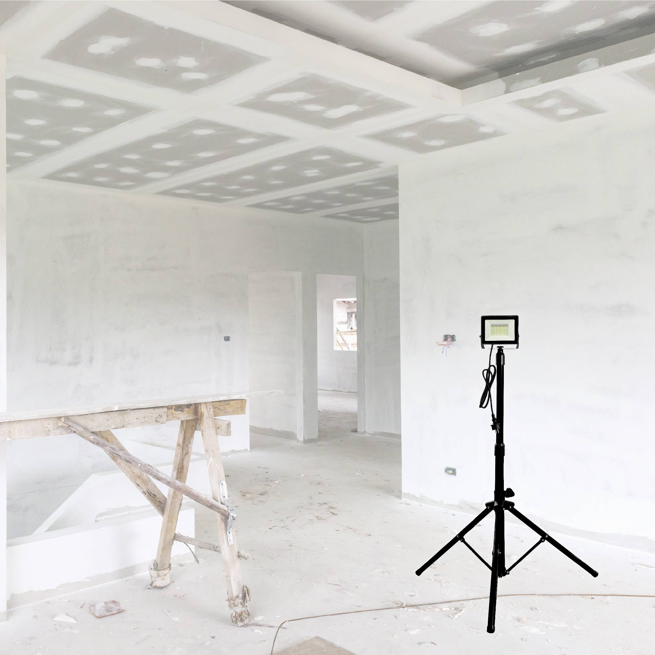 Pomieszczenie budowlane z białymi ścianami. W pomieszczeniu stoi drabina oraz statyw z urządzeniem pomiarowym. Widoczny charakter placu budowy.