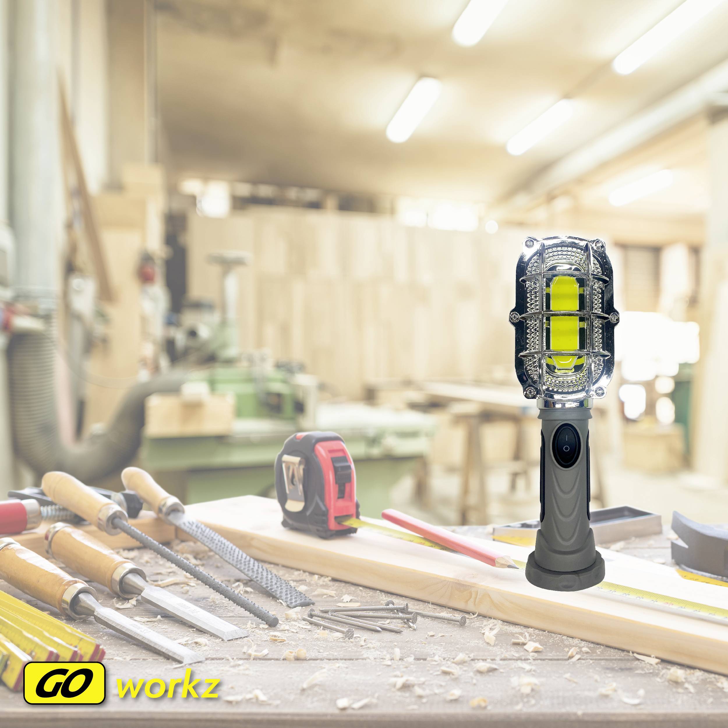 Warsztat rzemieślniczy z narzędziami na drewnianym stole. Na pierwszym planie stoi nowoczesna lampa robocza. Logo w rogu: 'GO workz'.