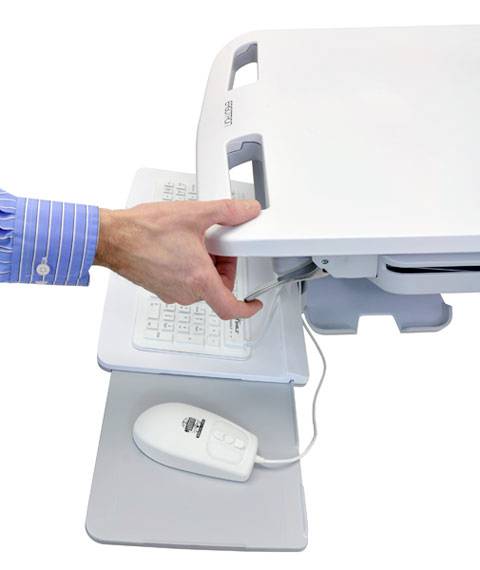 Ręka podnosi pokrywę białego wózka medycznego, aby uzyskać dostęp do klawiatury i myszy znajdujących się poniżej.