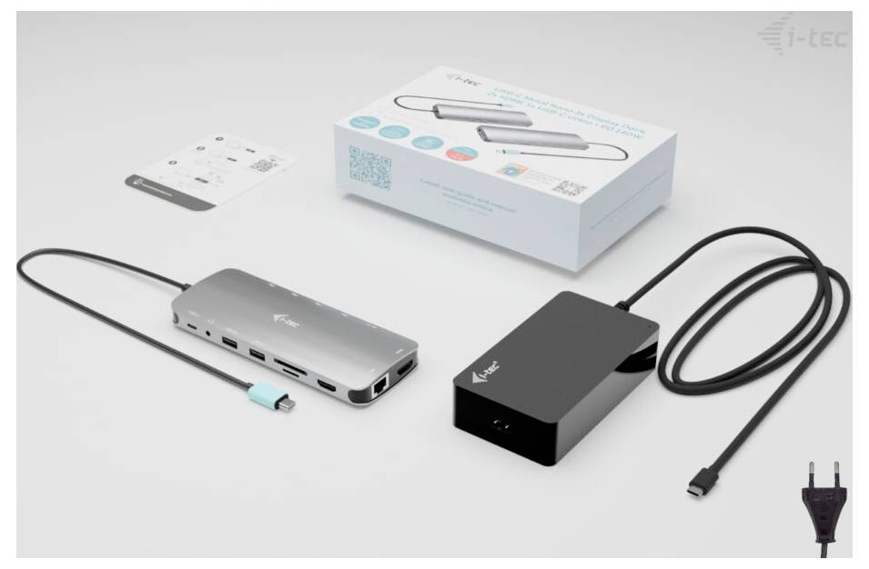 Stacja dokująca USB-C: Srebrne, prostokątne urządzenie z wieloma portami, podłączone do czarnego przewodu zasilającego. Na tle widoczne opakowanie i instrukcja.