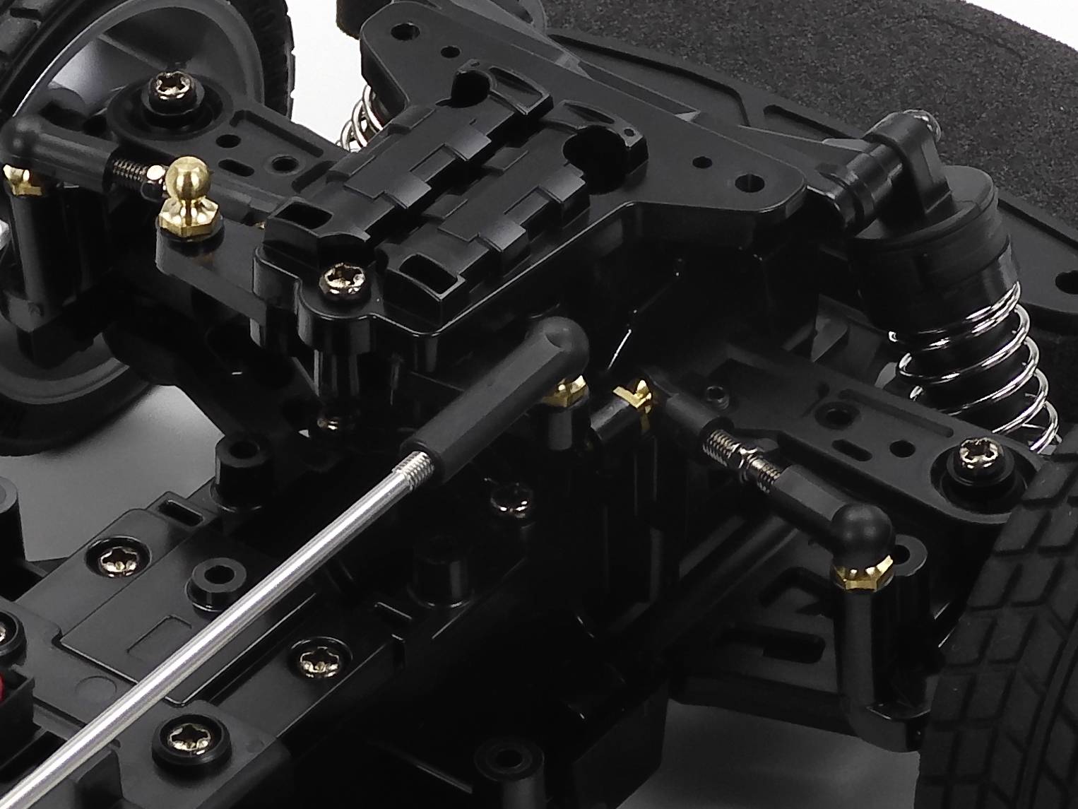 Zbliżenie technicznego elementu z sprężynami i mechanizmami dźwigniowymi. Prawdopodobnie jest to część pojazdu lub modelu.