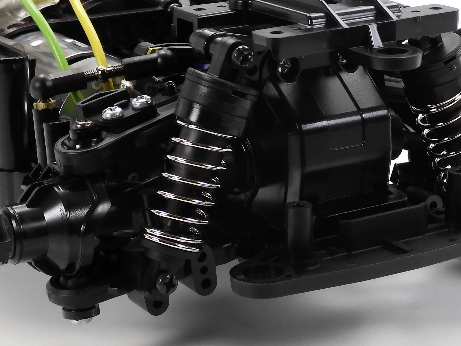 Zbliżenie czarnego elementu maszynowego z widocznymi sprężynami i przewodami, ujawniające szczegóły techniczne i budowę.